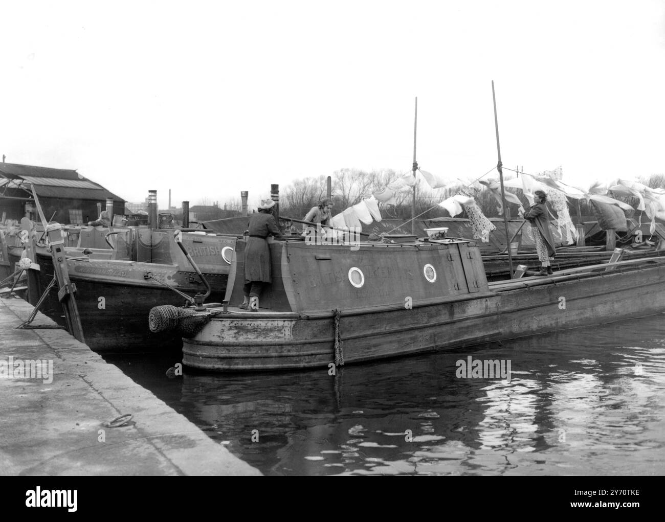Isleworth , Middlesex : Montag ist Waschtag für die Menschen , die von den Lastkähnen leben , genauso wie für die Hausfrau in der Vorstadt . Auf einem Kanal bei Isleworth stellt die Frau eines Bargees die Wäsche aus - ihr Kleidermast ist der Mast und ihr Weg die schmale Seite des Lastkahns. Aber ansonsten ist das Leben genauso - die Frauen unterhalten sich von Lastkahn zu Lastkahn und laden sich gegenseitig zu einer Tasse Tee ein! 1956 Stockfoto