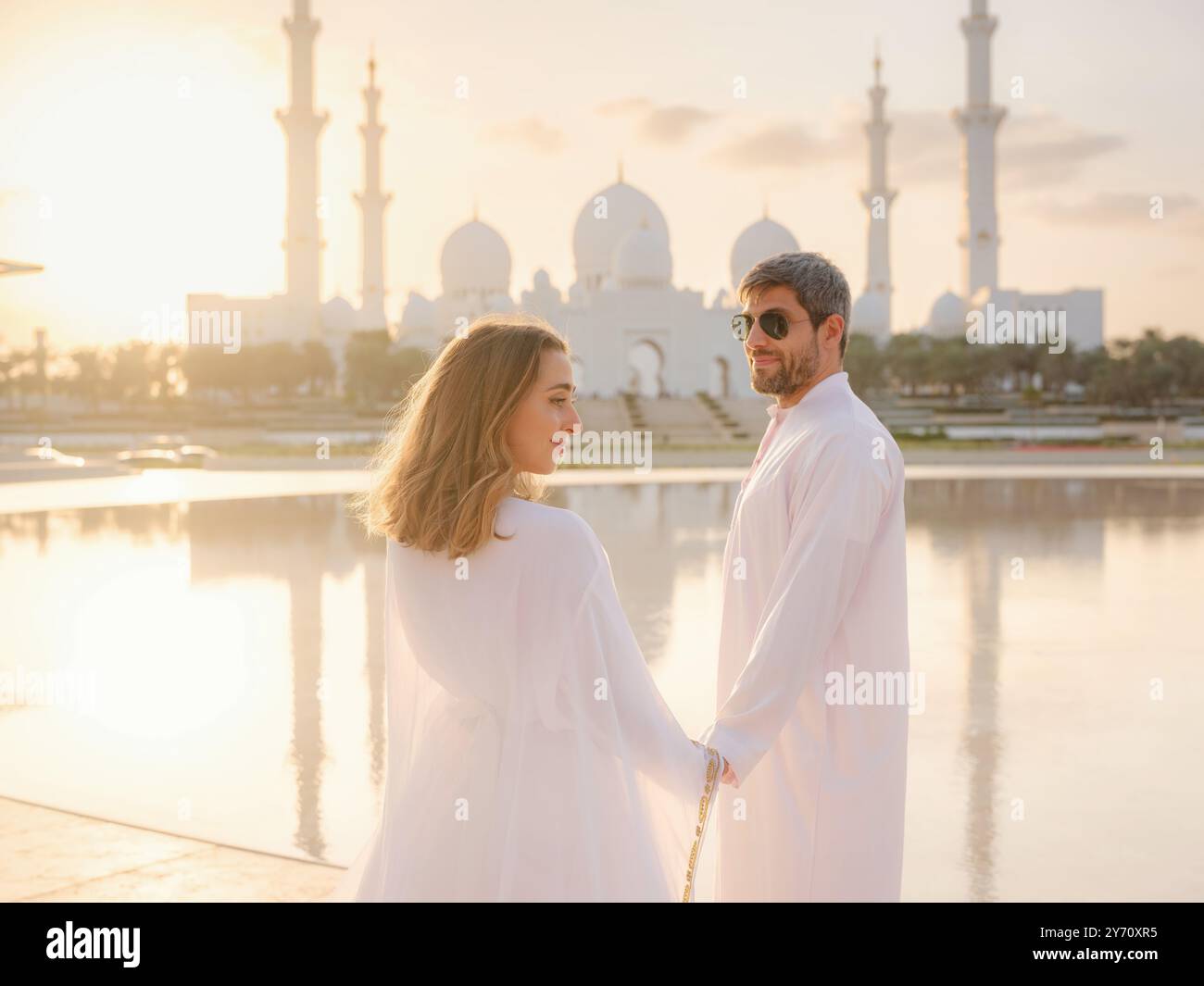 Reisen Sie in die Vereinigten Arabischen Emirate, Abu Dhabi. Arabisches Paar besucht den Park in der Nähe der Großen Moschee in Abu Dhabi in traditioneller Kleidung. Stockfoto