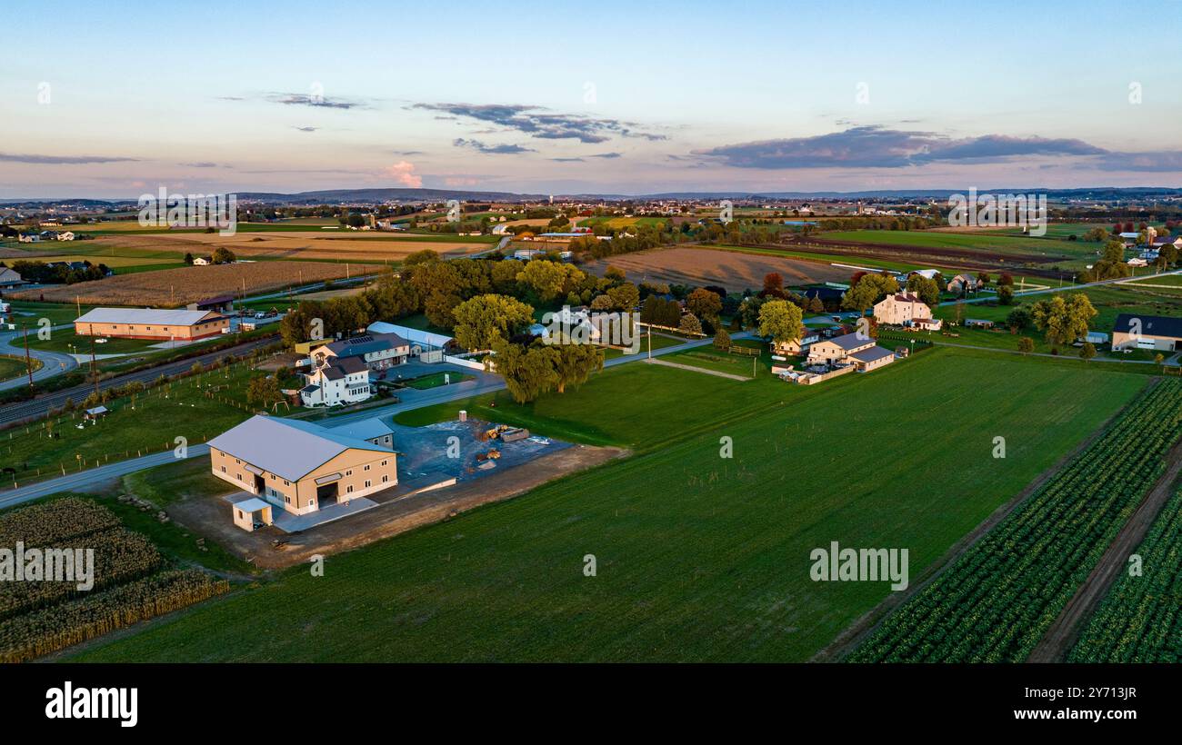 Ein weitläufiger Blick aus der Vogelperspektive fängt die ruhige Schönheit des ländlichen Pennsylvania bei Sonnenuntergang mit Ackerland, Bäumen und Wohngebieten ein. Die pulsierende Landschaft spiegelt die Ruhe des Landlebens wider. Stockfoto