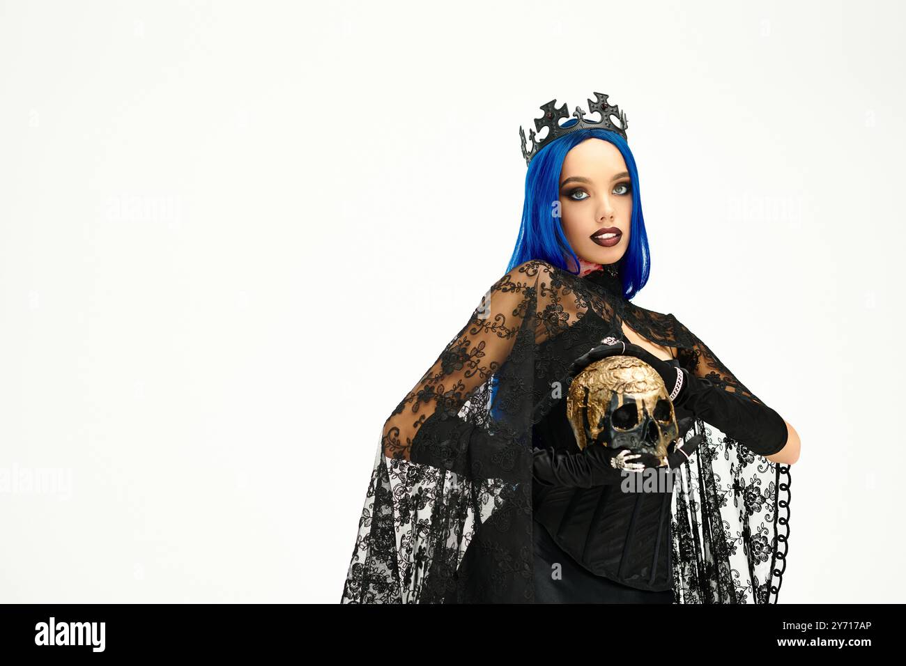 Eine junge Frau modelliert ihr atemberaubendes Gothic Halloween Kostüm mit einer auffälligen Krone und dunklem Make-up. Stockfoto