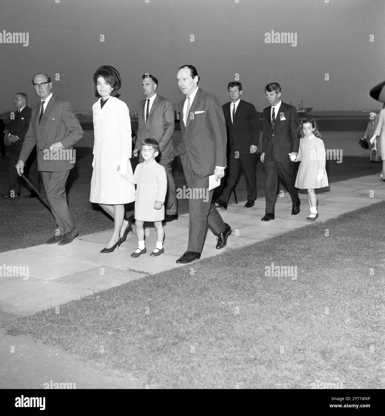 Mrs. Kennedy kommt zur Gedenkfeier. London Airport : die Bilder nach ihrer Ankunft sind von links nach rechts zu sehen : Mrs Jacqueline Kennedy , Sohn John Kennedy (4) , Lord Harlech , ehemaliger britischer Botschafter in den USA und dahinter Senatoren Edward Kennedy (links) und Robert Kennedy , die Hand von Mrs Kennedys Tochter Caroline ( 7) halten. Frau Kennedy und die anderen sind hier, um in Runnymede die Gedenkstätte für den verstorbenen Präsidenten zu enthüllen. 12. Mai 1965 Stockfoto