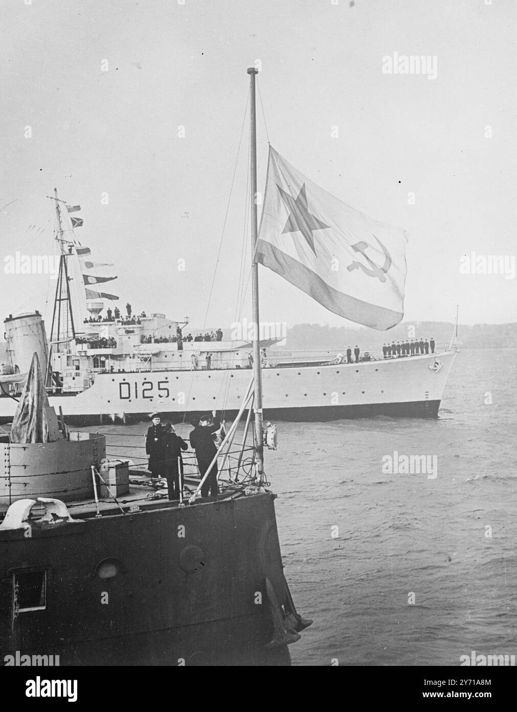 DER KÖNIGLICHE SOUVERÄN WIRD WIEDER H.M.S. das Schlachtschiff ROYAL SOUEIGN wurde offiziell von Russland an die Royal Navy in Rosyth in Schottland zurückgegeben . Die russische Flagge wurde kurz vor Sonnenuntergang durch die königliche Fähnrich ersetzt. In ihrer Nähe lag das Truppenschiff '' UKRAINA '' vor Anker mit 600 sowjetischen Offizieren und Soldaten , die heute nach Russland zurückkehren . DAS BILD ZEIGT :- der russische Fähnrich wird an Bord des KÖNIGLICHEN SOUVERÄNS heruntergezogen . Dahinter befindet sich der britische Zerstörer " NEPAL "" Flugsignal " Happy Return "" . 10. Februar 1949 Stockfoto