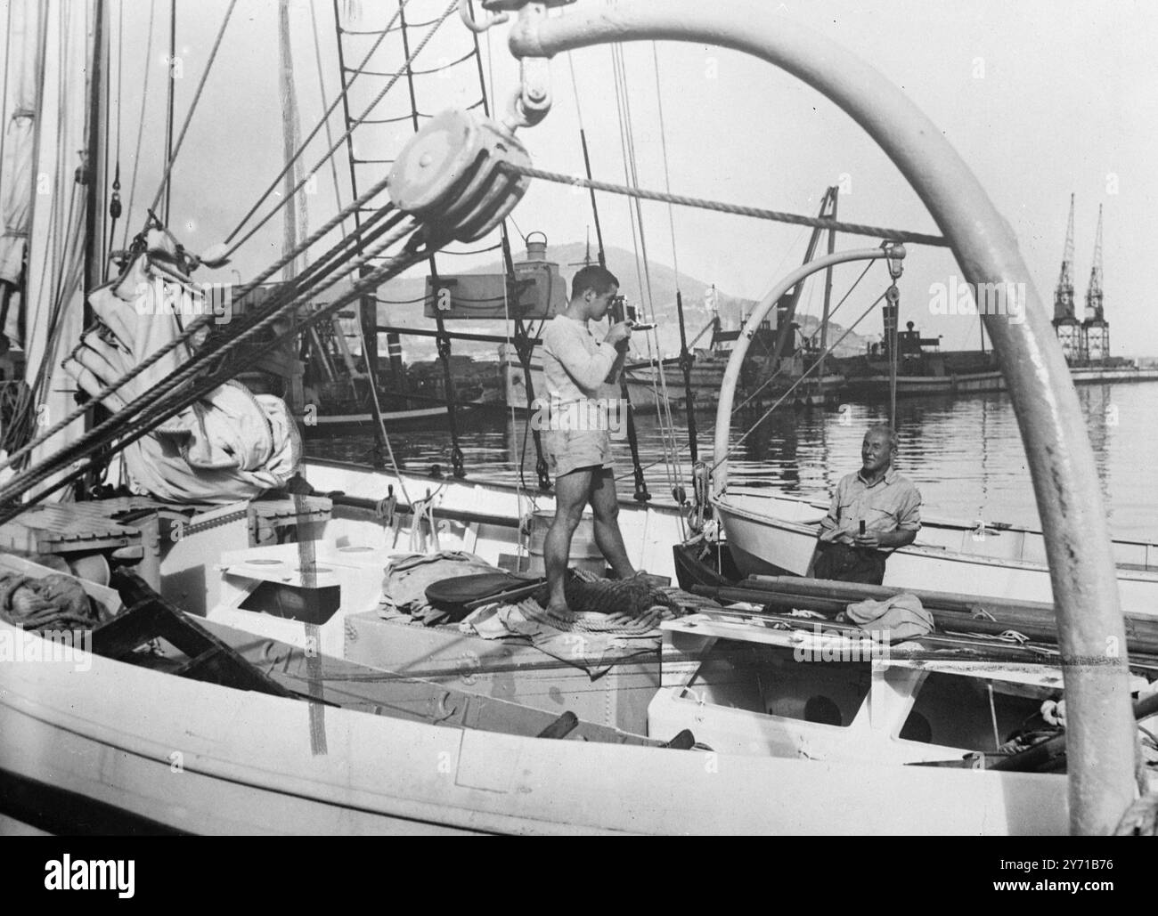 DIESE YANKS SEHEN Die WELT Eine Crew junger Amerikaner macht 1949 pro Jahr Abenteuer , denn sie reisen mit ihrer Yacht " Yankee " um die Welt . Bei der Ankunft im sonnigen Südafrika an Bord der Yacht in Table Bay macht HAZARD CAMPBELL Fotos für seine Aufzeichnung der Reise , während Commander JACK BRAIDWOOD , zweiter Mate , zusieht . 2. Februar 1949 Stockfoto
