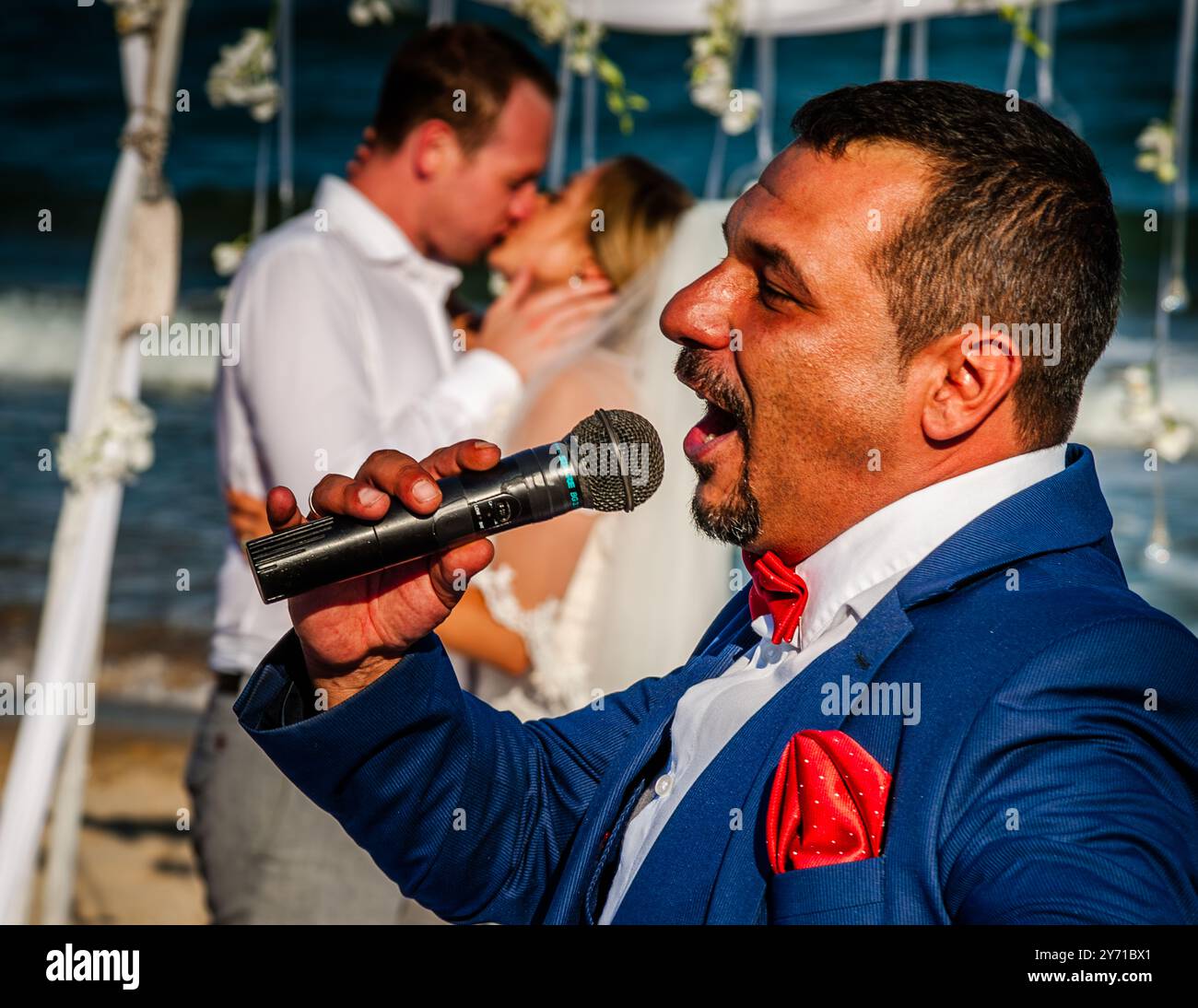 Hochzeit am Strand in Bulgarien. Der Zeremonienmeister animiert Braut und Bräutigam zum Hochzeitskuss am Strand des Schwarzen Meeres Stockfoto