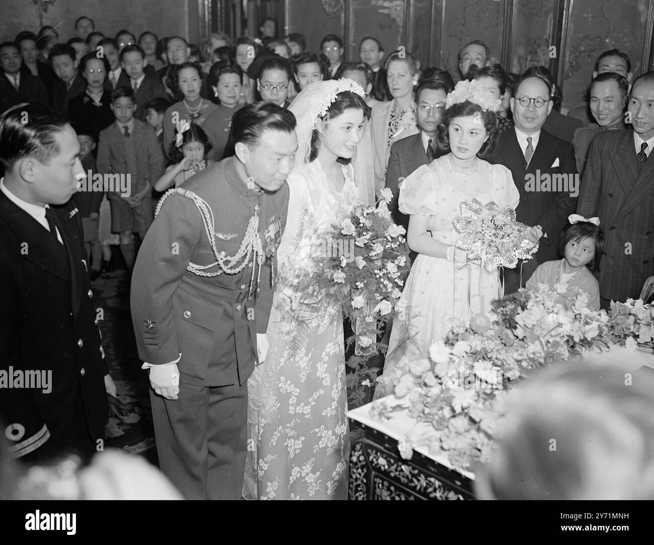 " CHINESISCHES DOPPELKIND " heiratete vor Tagen im Marylebone Register Office , Miss SHAO YING CHEO , ein schönes 18-jähriges chinesisches Mädchen , und Kampfpilotin tun YUNG CHENG haben heute in der chinesischen Botschaft in London geheiratet . Heutige Zeremonie, die von Dr . Cheng , der chinesische Ambasador , wurde in orientalischer Weise aufgeführt . FOTOSHOW :- die Braut mit einem Bukett stehend mit dem Bräutigam vor dem Altar während ihrer Hochzeitszeremonie heute mit Dr . Cheng der chinesische Botschafterbeamte . Juni 1948 Stockfoto