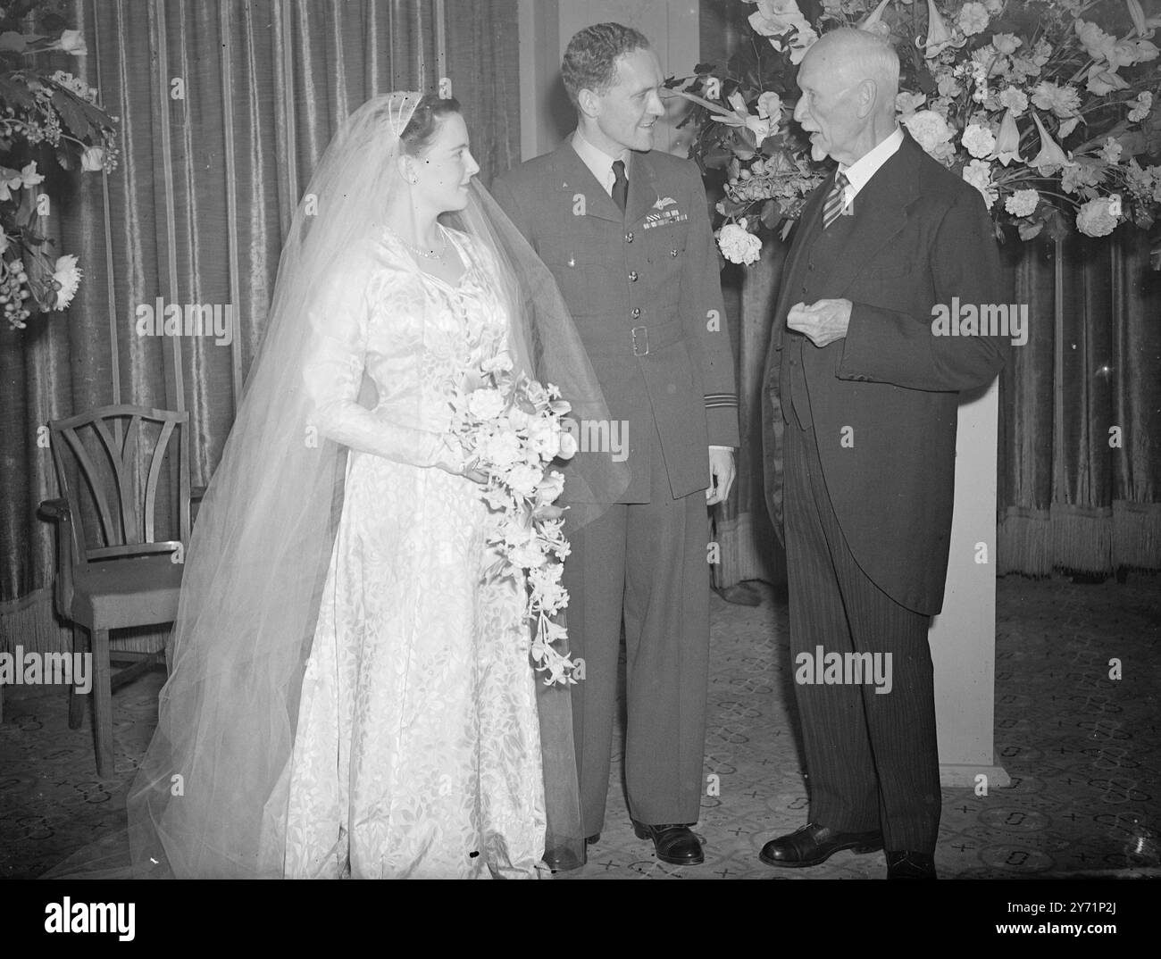 GENERAL SCHMUTIERT EINEN HOCHZEITSGAST. Einer der Gäste bei der Hochzeit von Miss JUDITH WELSH und Mr. ANTHONY HOLLAND, D F C, in St. Margarets Westmister heute war Feldmarschall Smuts . Herr Holland ist der Sohn von Sir Alfred Holland , dem Obermeister des Obersten Gerichtshofs ( Chancery Division ) . Seine zukünftige Frau Judith spielte mehrere kleine Rollen in Filmen wie " Bonnie Prince Charlie " und " Anna Karenina " . DAS BILD ZEIGT :- " freundlicher Rat " General Smut ( rechts ) . Hat ein freundliches Wort mit dem jungen verheirateten Paar bei ihrem Hochzeitsempfang in London. Stockfoto