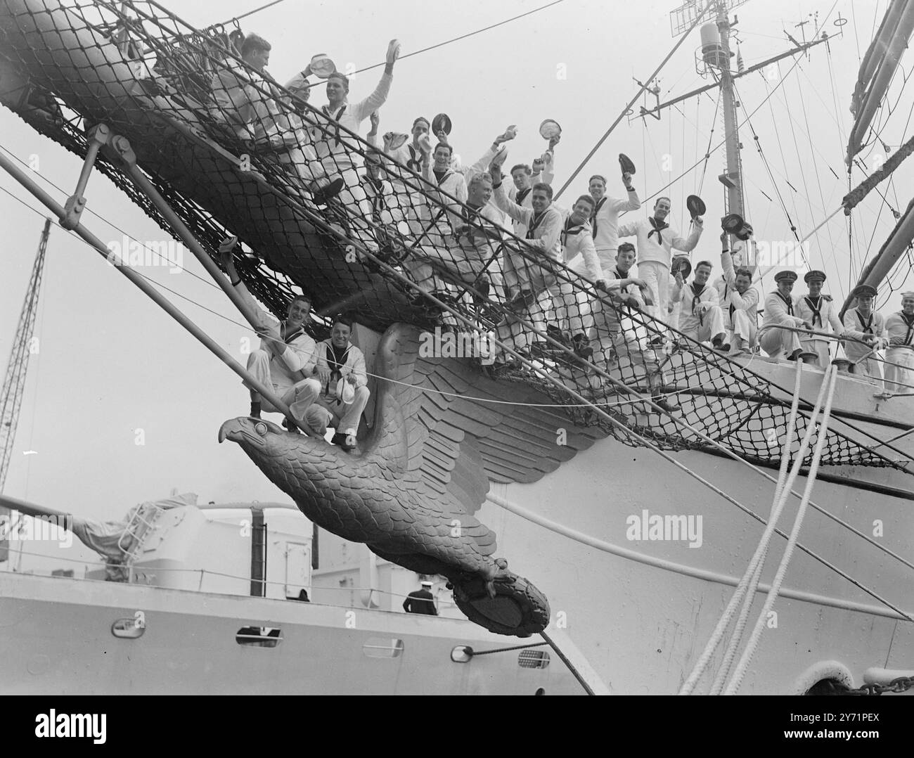 „Junior Salts“ – US-Schiffe auf Besuch die drei Mastbarque Eagle, ein amerikanisches Hilfsausbildungsschiff mit 170 Kadetten der United States Coastguard Academy, kam zusammen mit der US-Sloop Campbell nach London. Sie sind hier auf einer zehntägigen „Goodwill Training Cruise from America“. Das Bild zeigt: Geflügelte Seeleute Junge Marinekadetten grüßen England bei ihrer Ankunft im Shadwell Basin, London Docks, an Bord des Ausbildungsschiffs Eagle. Die beiden Salze auf der geschnitzten Galionsfigur sehen so viel wie ein Seemann zu Hause aus. Juli 1948 Stockfoto