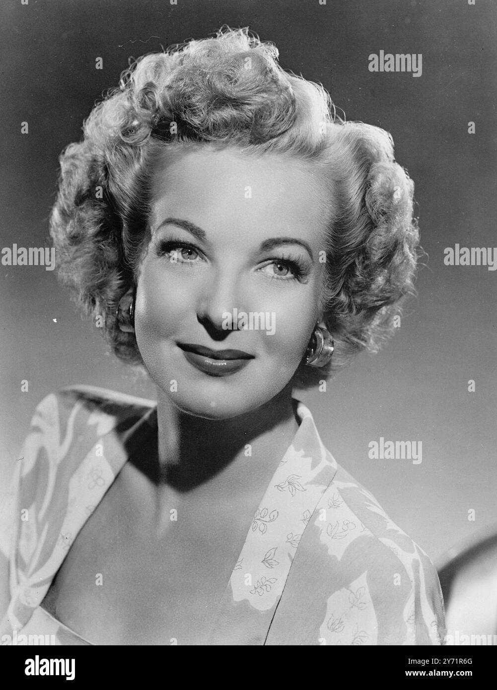 Der glamouröse HILLARY BROOKE, Columbian Pictures Star, hat eine neue Koniffure. Sie hat ihr Haar ganz kurz geschnitten ( 4 bis 6 Zoll lang) und in einem Halo von Nadellocken gesetzt , die alle zum Gesicht gerichtet sind. Wenn sie trocken waren, bürstete sie ihr Haar kräftig nach außen und die Enden drehten sich leicht unter, das obere Haar wurde gekämmt flauschige Locken, um einen Knall zu bilden. Hillary Brooke ist eine leidenschaftliche Sammlerin ungewöhnlichen Schmucks und glaubt, dass Einnahmen mit kurzen Haarfrisuren mehr denn je notwendig sind. Zu diesem Anlass trägt sie ein Paar Ohrringe im Stil einer schließe aus glänzendem Gold . Oktober 194 Stockfoto