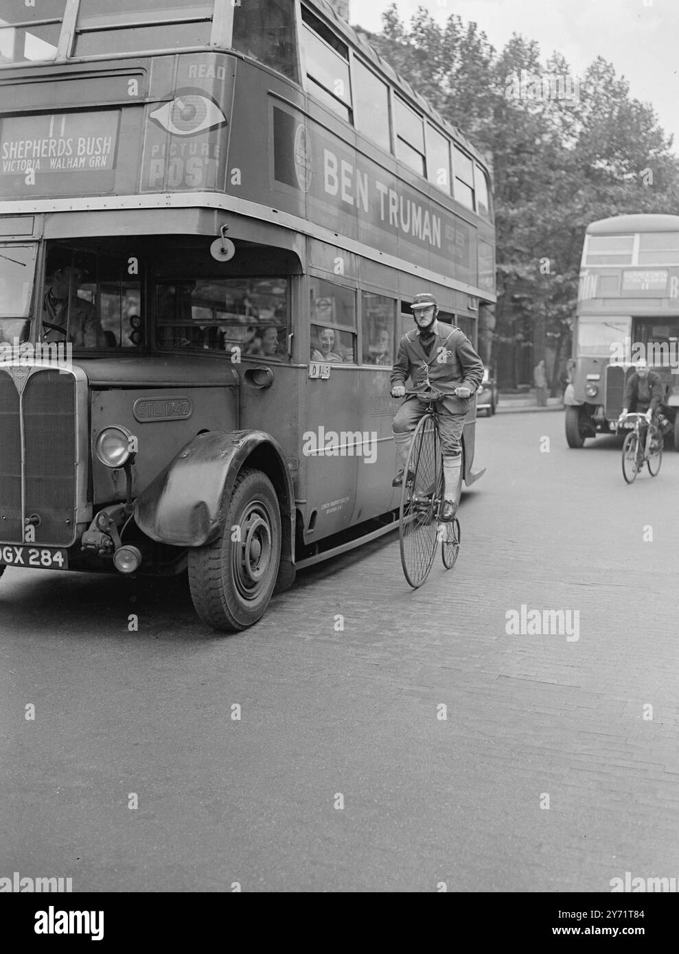 'London Transport' - um 1880, Herr J Blakoe, Sekretär des 'Old Ordinary Bicycle Club', verließ Temple Bar auf seinem treuen Penny Farthing Fahrrad, um die 'Sportsmen's Exhibition' in der Oxford Street zu besuchen. Mr. Blakoe trug ein Kostüm, das zu seinem Velocipede passte. Das Bild zeigt: "Penny Farthing Fare" - die Passagiere in diesem Londoner Bus waren mehr als ein wenig überrascht, als Herr Blakoe und sein Penny - Farthing sie heute in London überholten. Juli 1948 Stockfoto