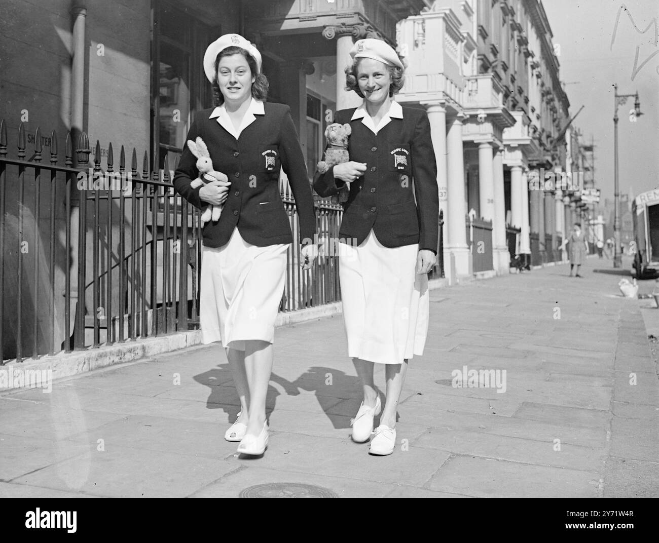 Britische Olympiatinnen gehen morgens spazieren. Die britische Olympiamannschaft der Frauen wurde gestern in ihrem Quartier am Eccles Ton Square in Westminster installiert. Heute Morgen wurden Mitglieder in Olympia-Uniformen zu einem Spaziergang gesehen. Das Bild zeigt:- Frau Dorothy Tyler (rechts) mit ihrem Löwenjungen Maskottchen, das sie zu den letzten Olympischen Spielen nach Berlin begleitete, auf dem Bild mit Frau Burt Pfeife, die heute Morgen beim Gehen gesehen wurde. 29. Juli 1948 Stockfoto