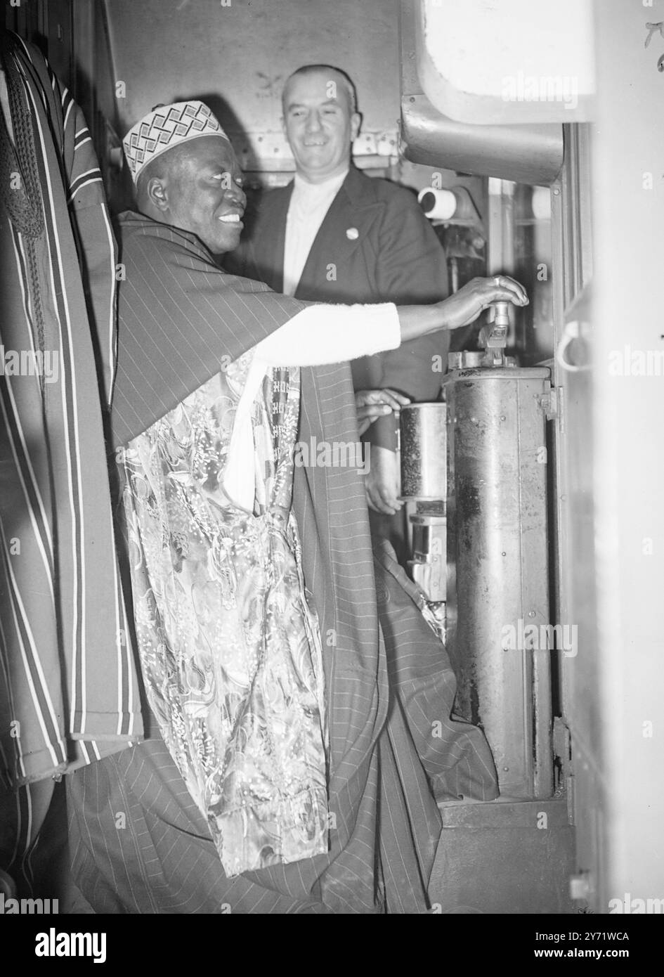 Der Oni geht in die U-Bahn. Die Oba Aderemi, Oni of Ife, spiritueller Leiter des Staates Yuruba Nigeria, der zu einem offiziellen Besuch in London ist, machte eine Tour durch das Londoner U-Bahn-System. Das Bild zeigt: 'Die Oni in Kontrolle' die Oni of ife hat heute Morgen eine Kurve an den Kontrollen eines Londoner U-Bahn-Zuges gemacht und sie von der Leicester Square Station in Kennington gefahren. August 1948 Stockfoto