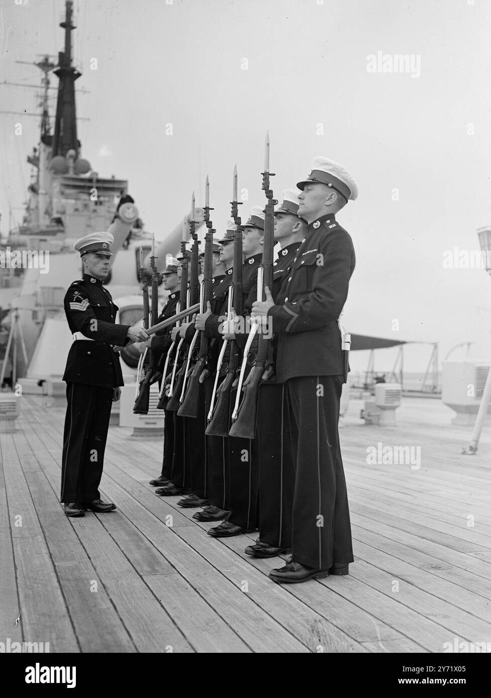 Avantgarde bereitet sich auf die Royal Australian Tour vor. Die Besatzung der HMS Vanguard freut sich mit großer Vorfreude auf die Royal Tour durch Australasien im nächsten Jahr und ist zu Recht stolz auf ihre Verbindung mit diesem großartigen Schiff, das jetzt in der Weymouth Bay (Dorset) liegt. Vor einer Shakedown-Kreuzfahrt nach Gibraltar und Malta am nächsten Freitag. Das Schiff erhält den letzten Schliff für die Tour, die sie zurück nach Devonport bringt. Das Bild zeigt: Sergeant G Easingwood, von Deal, bohrt Royal Marine Wachen, die auf der Royal Gangway während der Royal Tour nächstes Jahr im Dienst sein werden. 10. September 1948 Stockfoto