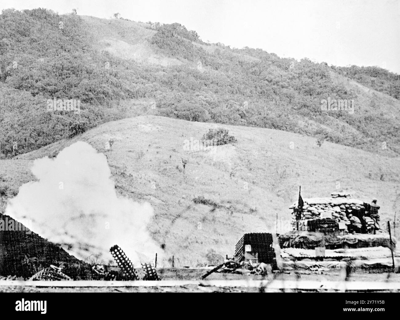 Khe Sanh , Südvietnam : während eine kommunistische Mörsergranate explodiert (links) versucht ein Späher der United States Marine , geschützt hinter einem schwer mit Sandsäcken bestückten Bunker (rechts) am 8 . februar 1968 die Stelle zu finden , an der die Muscheln von hier aus kommen . Die kommunistische Artillerie setzte sich auf Khe Sanh ein, da die Marines bereit blieben, die Basis gegen den erwarteten Angriff auf Vietnam am 15. Februar 1968 zu verteidigen Stockfoto