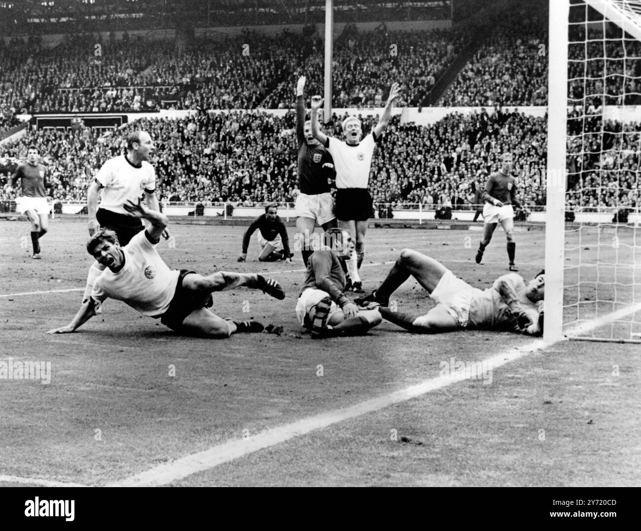 Das Tor, das Wembley1966 Fußball-WM-Finale Wolfgang Weber aus der Bundesrepublik Deutschland erschütterte, schreit aus dem Boden, nachdem er in den letzten Sekunden der normalen Zeit einen Ausgleich erzielt hatte. Auch in den weißen Hemden für die Bundesrepublik Deutschland sind Uwe Seeler (links) und Karl-Heinz Schnellinger (Mitte). Für England ist Ray Wilson neben Torhüter Gordon Banks auf dem Boden, Captain Bobby Moore ist in der Mitte attraktiv mit Jack Charlton (hinten rechts) und George Cohen (hinten rechts) am 30. Juli 1966 Stockfoto