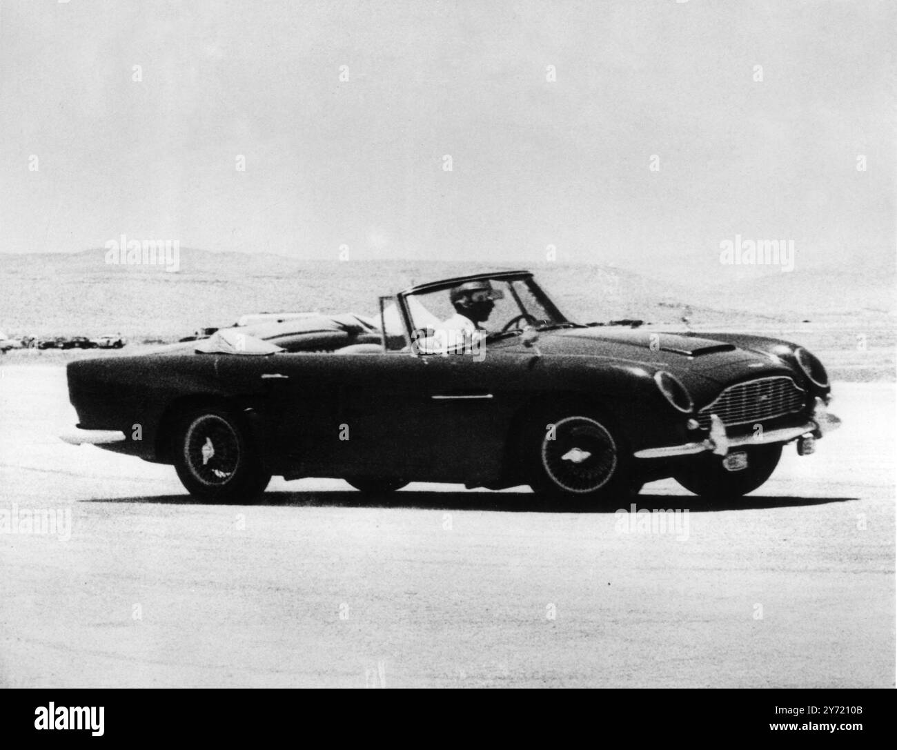 "Speed King" für Großbritannien. Amman , Jordanien : der sportliebende König Hussein von Jordanien , der auf diesem aktuellen Bild am Steuer seines Aston Martin zu sehen ist , wird am 19 . Juli Großbritannien zu einem zehntägigen Staatsbesuch besuchen . Er wird von seiner in Großbritannien geborenen Frau Prinzessin Muna begleitet. Während ihres Besuchs werden sie an einem Halbfinale des Fußballturniers der Weltmeisterschaft im Londoner Wembley Stadium teilnehmen . 28. Juni 1966 Stockfoto