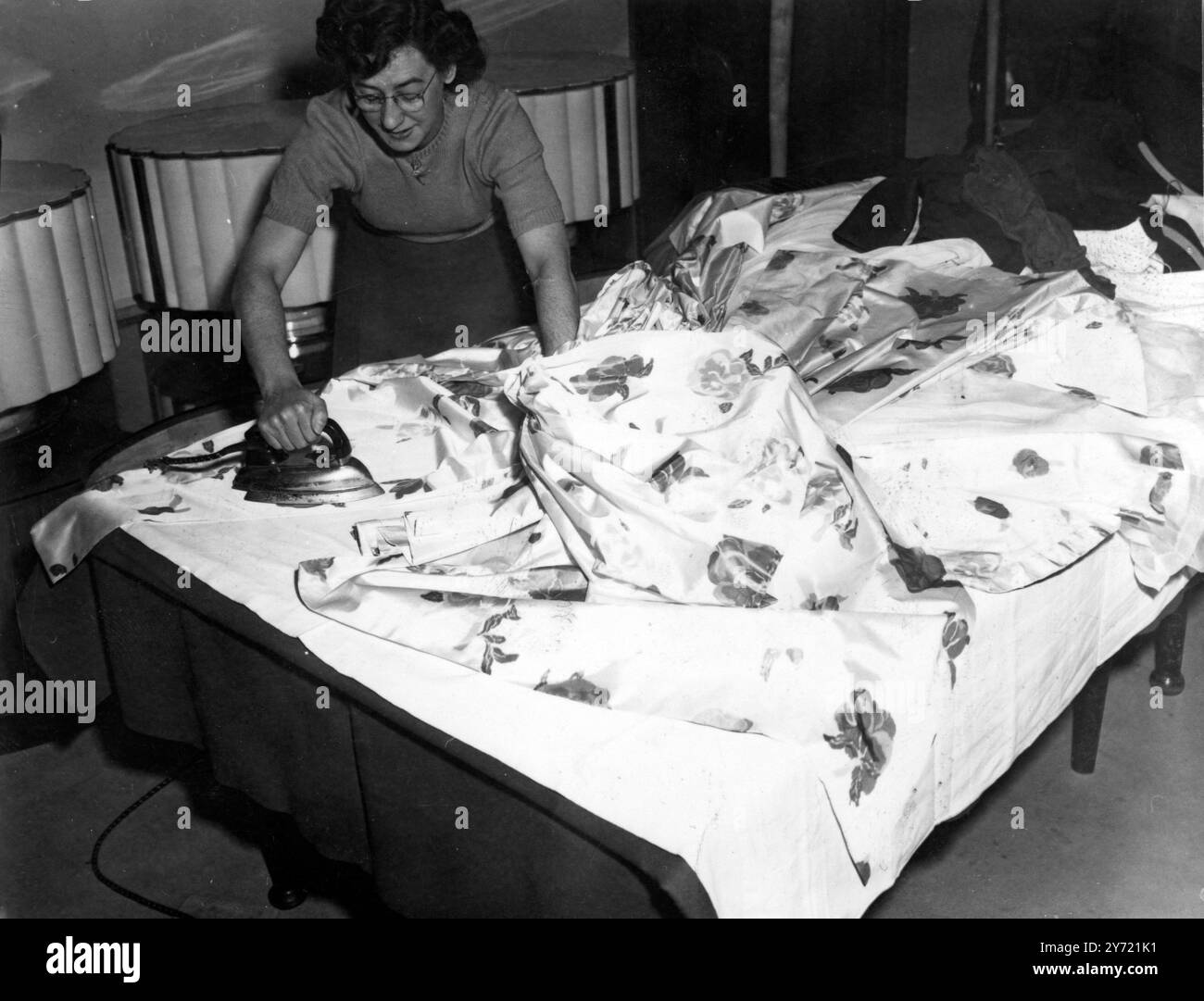 Die neuen Moden von Christian Dior , die in dieses Land geflogen wurden , werden jetzt im Savoy Hotel ausgepresst und sind bereit für die Modeschau dort . Jedes Kostüm ist mit einem speziellen Siegel versehen , und nachdem die Show nach Paris zurückgebracht wird , hat die fünf Tonnen schwere Kollektion einen Wert von 27 000 £ . Hier ist einer der Presser zu sehen, der eines der Kostüme für die Show vorbereitet. 24. April 1950 Stockfoto