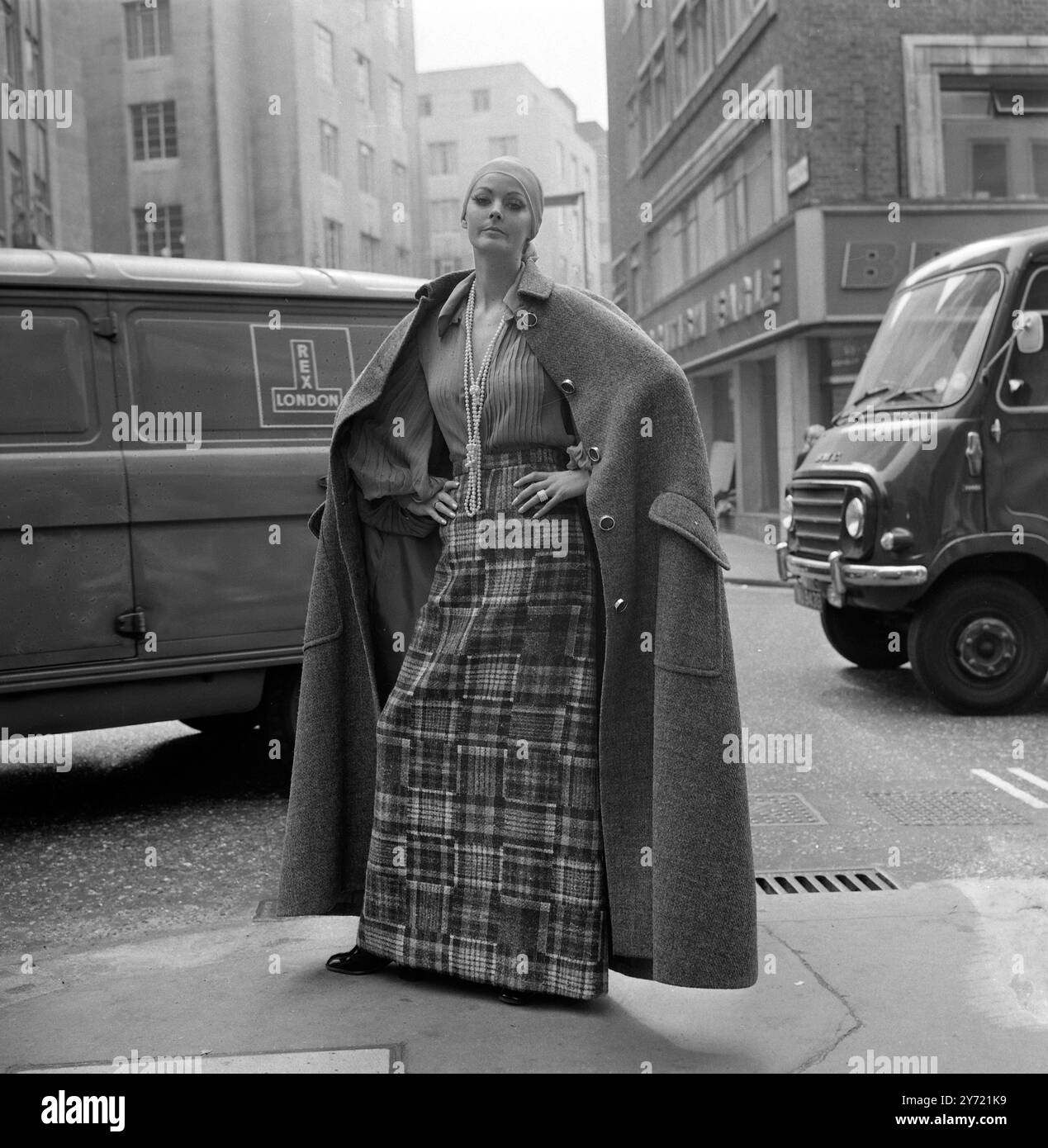 Das Model Girl Suzy befindet sich in einem ärmellosen, bodenlangen grauen Tweed-cape in der Conduit Street vom Christian Dior - London Fashion House entfernt . Kurz darauf machte sie die fünf geformten Knöpfe auf, um einen grauen Tweed-Patchworkrock und eine graue Chiffonbluse zu sehen, die „zu Hause“ getragen werden sollte. Das cape , der Rock und die Bluse stammen aus der neuen Sammlung des Autumn 1969 von Christian Dior - London . Die Sammlung wurde von Jorn Langberg veredelt. 9. September 1969 Stockfoto