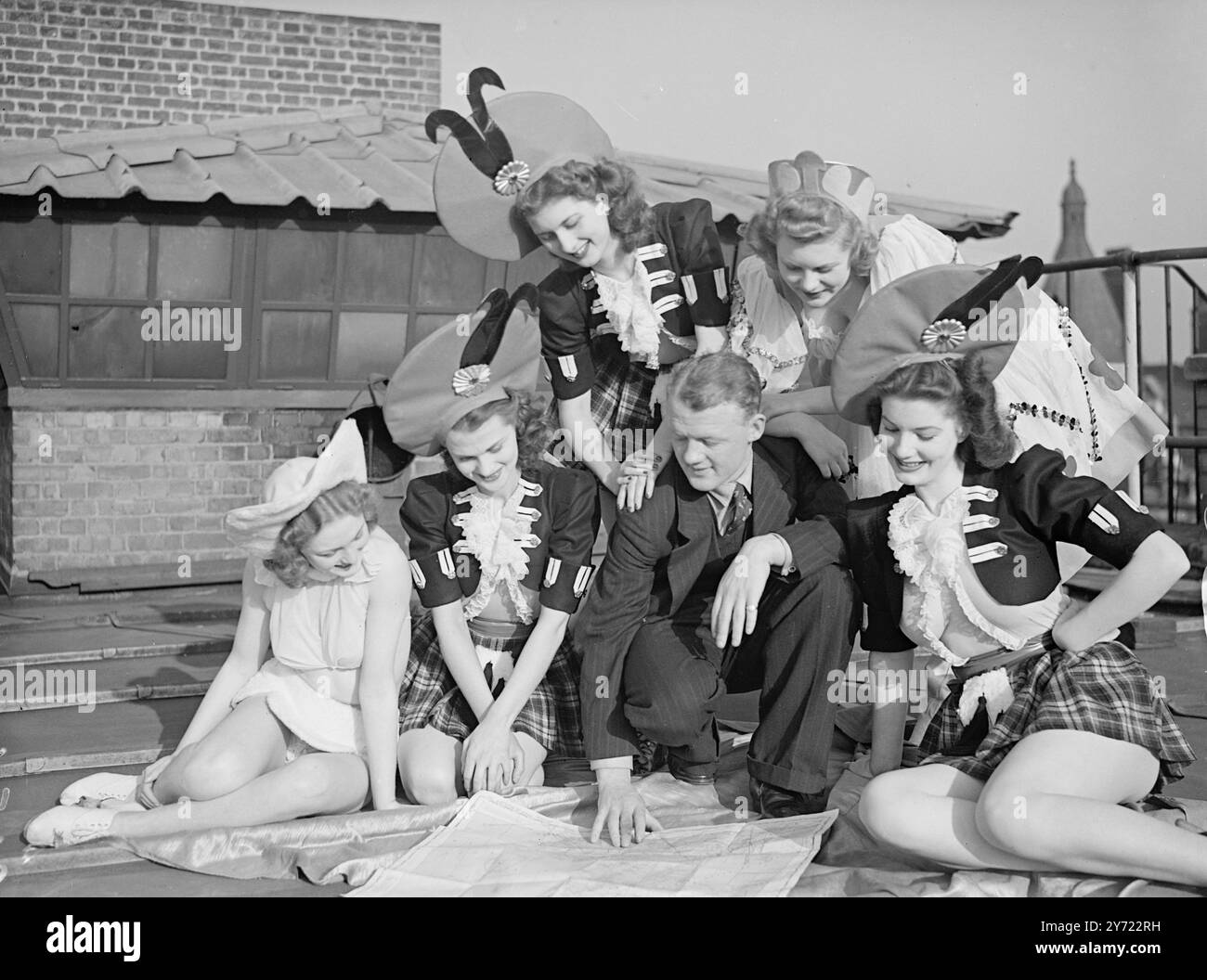 Das Windmühle-Mädchen geht um die Welt. Ab Prestwick (Schottland) am 1. April. In einem 200 H. P. Single Motor Percival Proctor, Windmill Girl, 27-jähriger neuseeländischer Ex-RAF-Pilot, nachdem Mansfield mit durchschnittlich 70 km/h um die Welt fliegen will. Er hofft auch, in 17 Tagen Rekorde durch die Tatsache in Northolt zu brechen. Als Besucher des Windmill-Theaters benannte Herr Mansfield sein Flugzeug nach den Mädchen, die immer „weitermachen“. Das Bild zeigt: 'Flugzeugschönheiten' - in der Frühlingssonne auf dem Dach des Windmill Theaters, Pilot des Mansfield 'holt das Gen' von Windmill Girls - links nach rechts: Maureen O'DEA Stockfoto