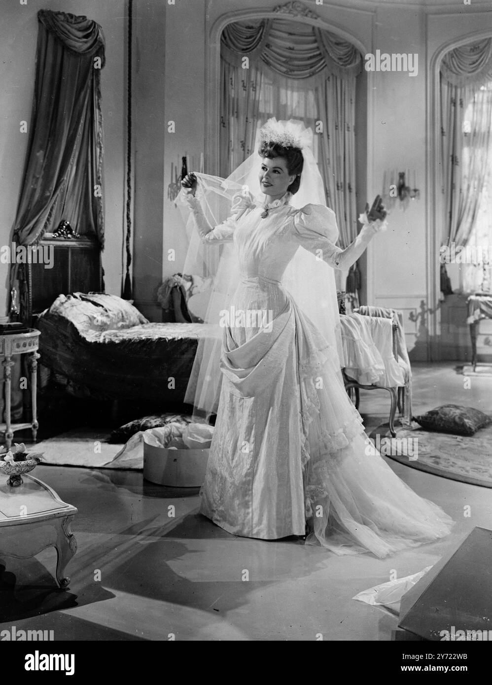 Edwardianische Braut. Die hübsche, hellhäutige Sally Gray, die die ansprechende Sara Bonheur in dem Melodram „Mark of Kain“ der 2 Städte spielt, ist eine edwardianische Braut, mit all der Delikatesse und dem Charme, die diese liebenswürdige Zeit vermittelt. Ihr Kleid hat eine kleine aufrechte Rüsche um den Hals, gefangen von einer antiken Perlenbrosche. Die Beine der Hammelärmel sorgen für eine ausgewogene Balance zwischen der drapierten und zerrissenen Hüftlinie, die in einen leichten Zug Tüll übergeht. Sallys Haare stapeln sich in den Knall der Zeit, und ihr schäumender Tüll und Orangenblüten-Kopfschmuck reitet hoch auf ihrem Kopf und endet in einer kurzen Steife Stockfoto