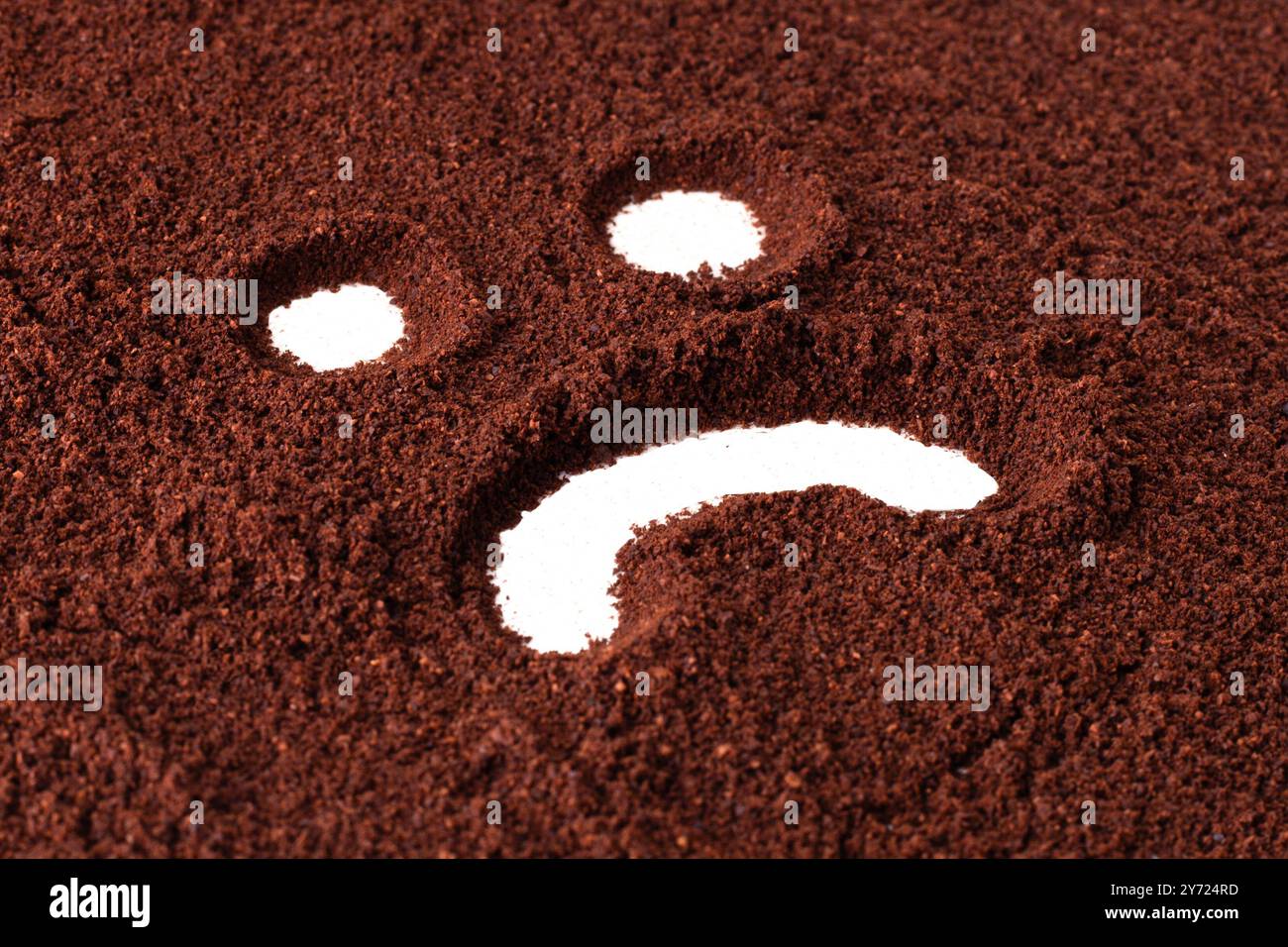 Trauriges Gesichtssymbol, in Kaffeepulver gemalt. Stockfoto