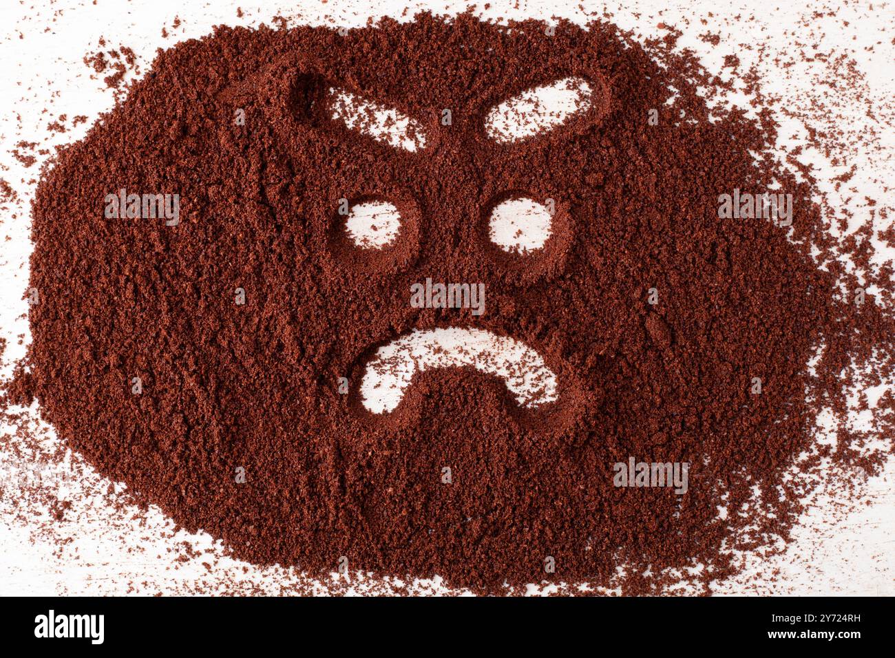 Wütendes Gesichtssymbol, in Kaffeepulver gemalt. Stockfoto