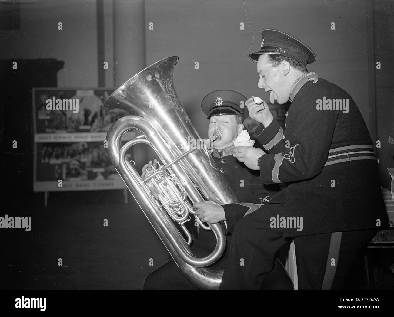 SAMSTAG BANDSTAND 72 Bläserbands aus Countys in ganz Südengland versammelten sich heute (Samstag) in Central Hall in Westminster für den Qualifikationswettbewerb der London and Southern Counties Area bei der National Brass Band Championship of Great Britain 1948. DAS BILD ZEIGT: Versuchung. Bandsman LEN WALPOLE von der Weymann Works Band, Addlestone, Surrey, versucht seinen Kollegen GORDON ROOKE heute Morgen mit einem riesigen Eis in der Central Hall vom Kontrabass zu verführen. 7. Februar 1948 Stockfoto