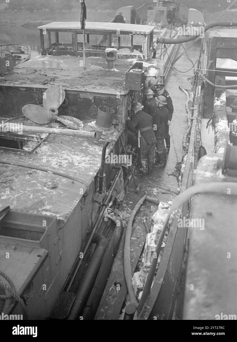 Ein Toter ein Mann soll getötet und mehrere seiner Gefährten verletzt worden sein, als der mit Erdöl beladene Motorkahn John Harker heute früh am Dienstag bei Avonmouth Docks in Bristol explodierte. Die schnelle Arbeit der Feuerwehrleute, die die Ergebnisse im Schiff bekämpften, verhinderte, dass sich die Flammen auf den vorderen Teil des Lastkahns ausbreiten konnten. Der vermisste Mann, Mr. Harry Hopwood, der Ingenieur, war zum Zeitpunkt der Explosion im Maschinenraum. Andere Mitglieder der Crew, die versuchten, ihn zu retten, wurden mit einer Masse von Flammen zurückgetrieben. Das Bild zeigt: Feuerwehrleute, die das mit Schaumstoff bedeckte Petrol inspizieren Stockfoto