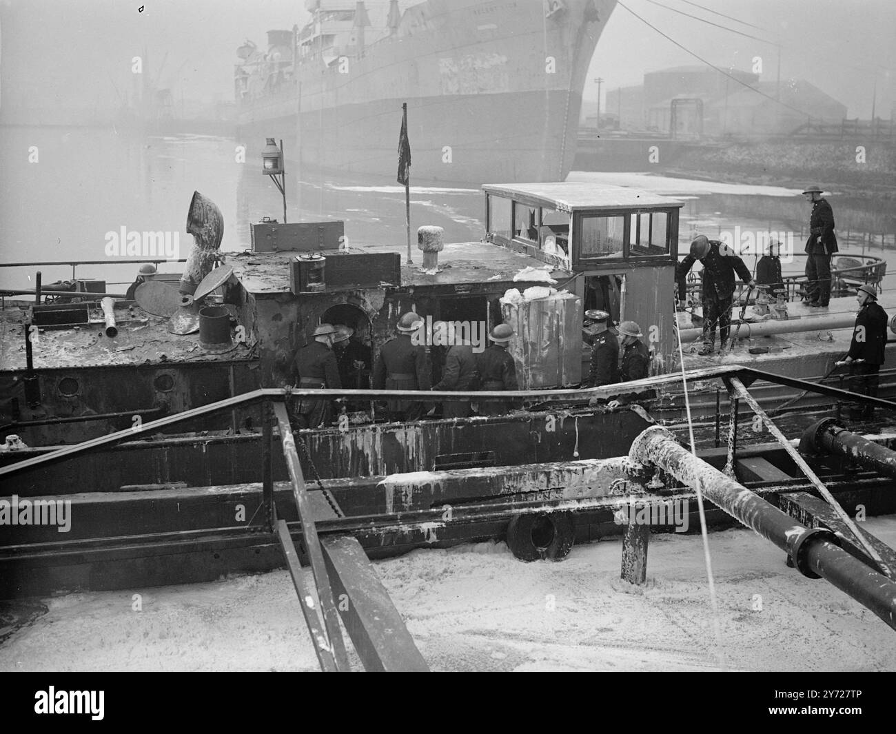 Ein Toter ein Mann soll getötet und mehrere seiner Gefährten verletzt worden sein, als der mit Erdöl beladene Motorkahn John Harker heute früh am Dienstag bei Avonmouth Docks in Bristol explodierte. Die schnelle Arbeit der Feuerwehrleute, die die Ergebnisse im Schiff bekämpften, verhinderte, dass sich die Flammen auf den vorderen Teil des Lastkahns ausbreiten konnten. Der vermisste Mann, Mr. Harry Hopwood, der Ingenieur, war zum Zeitpunkt der Explosion im Maschinenraum. Andere Mitglieder der Crew, die versuchten, ihn zu retten, wurden mit einer Masse von Flammen zurückgetrieben. Das Bild zeigt: Feuerwehrleute, die das mit Schaumstoff bedeckte Petrol inspizieren Stockfoto