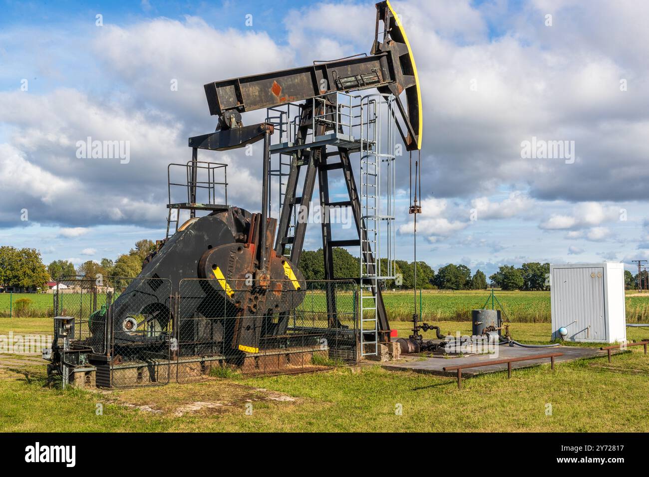 Öltiefpumpe „Pferdekopf“. Ölvorkommen wurden auf der Halbinsel Gnitz in den 1960er Jahren entdeckt, als Erdöl im Rahmen der DDR-Selbstversorgungsbemühungen erforscht wurde. Der erste erfolgreiche Brunnen wurde 1965 gebohrt und die Produktion begann 1966. Das Öl wird aus einer Tiefe von rund 2.400 bis 2.600 Metern gewonnen und stammt aus dem Staßfurter Zyklus des Zechsteins, einem geologischen Stausee mit einer Dicke von rund 80 Metern. Dorfstraße, Am Peenestrom, Mecklenburg-Vorpommern, Deutschland Stockfoto