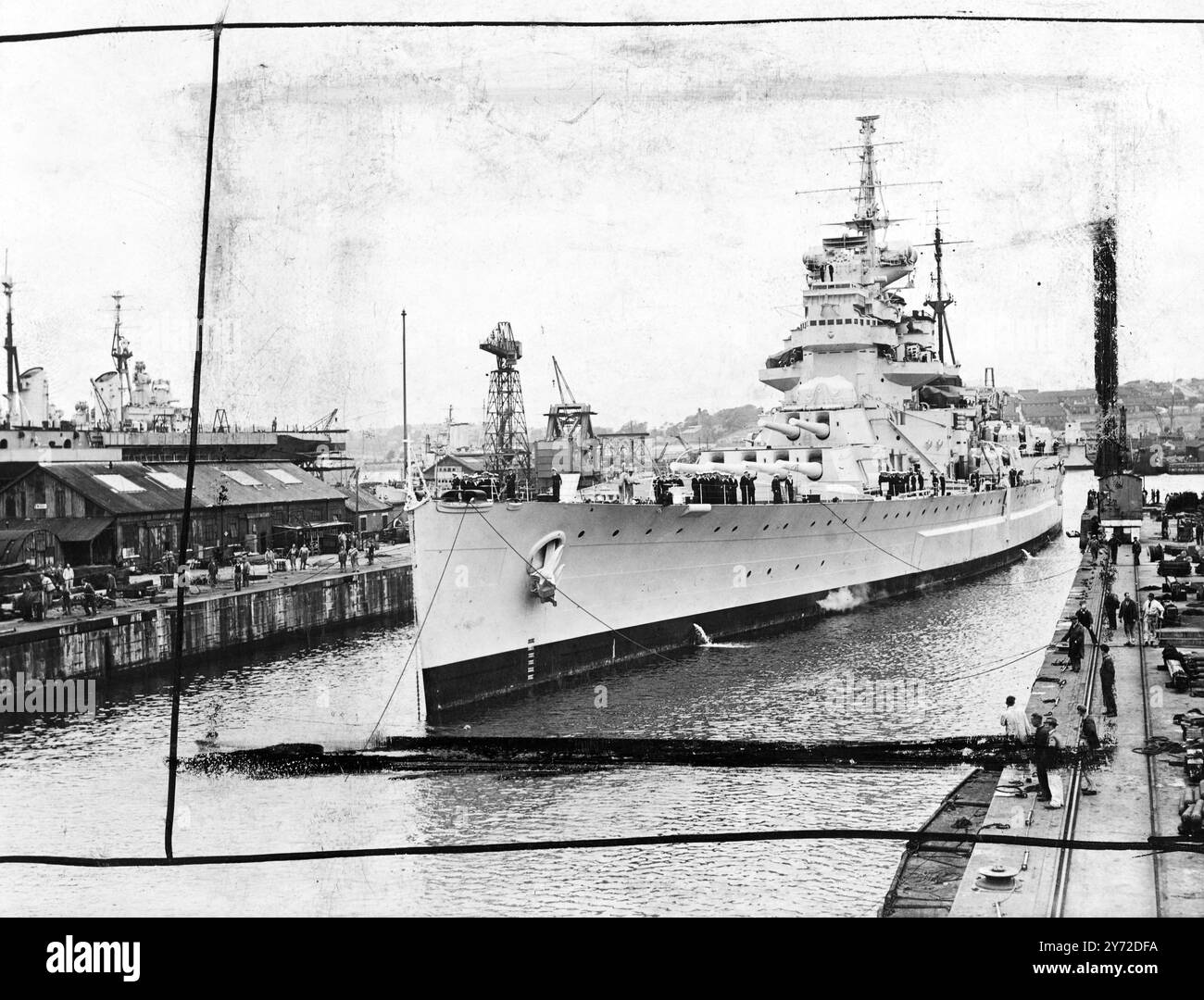 Das 35.000 Tonnen schwere Schlachtschiff der King George V-Klasse, HMS Anson, wird langsam in das Trockendock von Devonport eingedrungen. Das Flaggschiff der Flaggenoffiziere, die Schlachtschiffe der Anson. Seit ihrer Anstellung im Jahr 1942 war sie in verschiedenen Kriegsschauplätzen tapfer gedient. Ihre erste Rolle war die des Flaggschiffs der Zweiten Kampfgeschwader, die den Schutz von Konvois nach Russland überwachte, und sie wird für ihren Angriff auf das deutsche Taschenschiff Tirpitz im Kaa-Fjord 1944 in Erinnerung bleiben, als dem Stolz der deutschen Marine schwere Schäden zugefügt wurden. Anfang 1945 wurde sie Flaggschiff Stockfoto