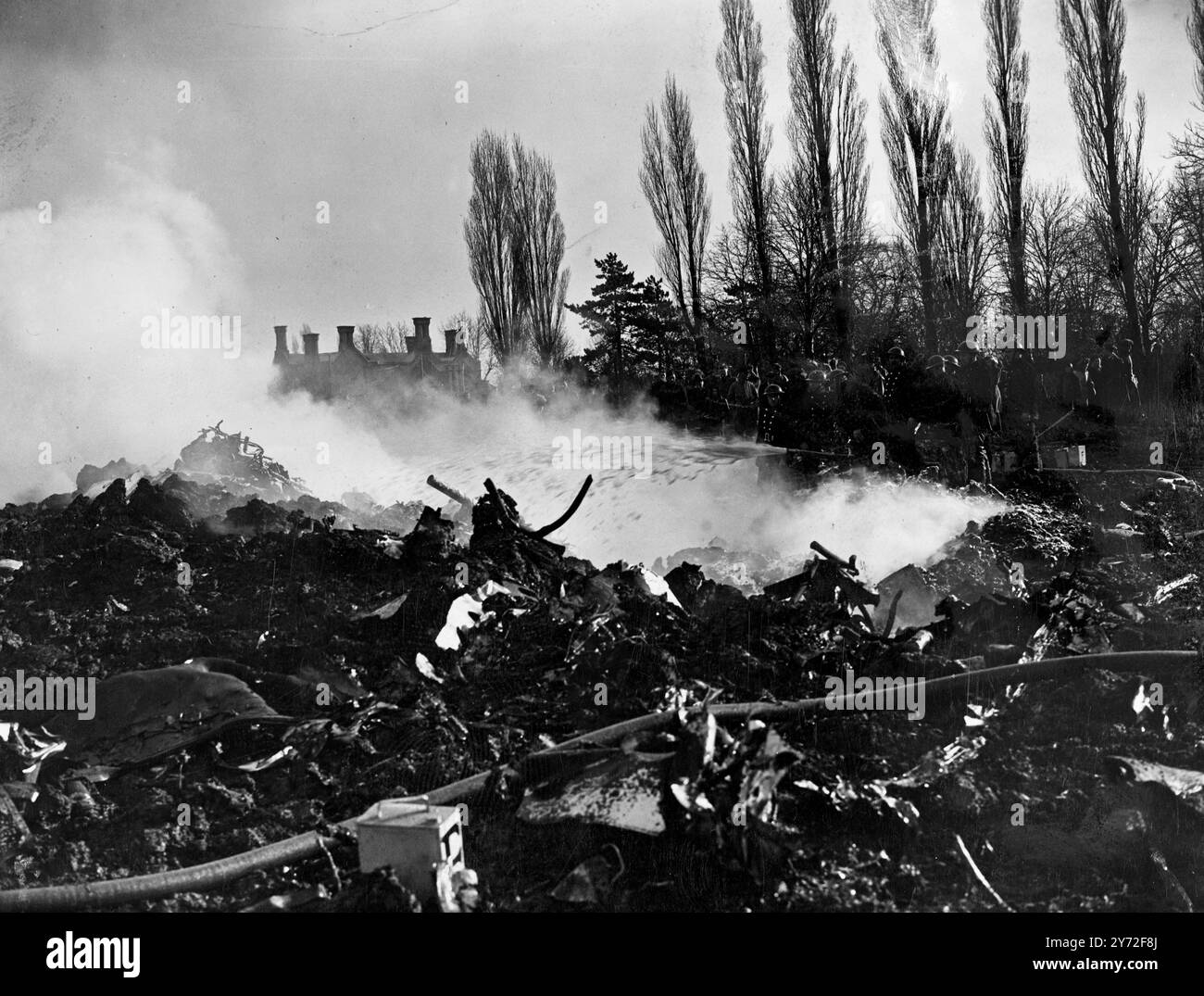 Mit Motoren, die stottern und Flammen aus ihr strömten, stürzte ein Lancaster-Bomber in der Long-Street und Aylestone Lane, Vigston Magna, Leicestershire, heute Nachmittag, Montag ab. Ein heftiges Gewitter mit Sturm war zu dieser Zeit im Gange. Das Bild zeigt: Feuerwehrleute spielen Schaum in den Krater, verursacht durch das abgestürzte Flugzeug. 4. Februar 1946 Stockfoto
