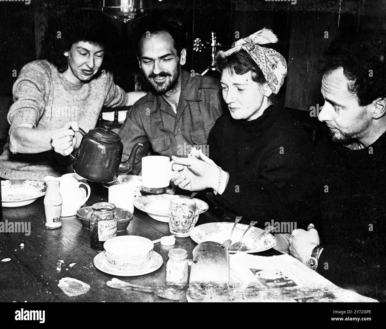 Fünf Leute brechen von Gourock auf, um die gefährliche 5500 Meilen lange Reise nach Amerika in 63 Fuß Yawl White Cloud zu versuchen. Neuer Kapitän des Schiffes ist der 22-jährige zweite Kamerad Roderick Finlayson aus Ross-shire, Schottland. Mit ihm geht es zu jungen Ex-Piloten der amerikanischen Luftwaffe und ihren Frauen. Gestern war die Party damit beschäftigt, die letzten Vorbereitungen für den langen Film zu treffen. Wenn alles gut läuft, hoffen sie, Anfang September in Maine anzukommen. Das Bild zeigt: Eine Mahlzeit an Bord der White Cloud, bevor sie Gourock verlassen. Die beiden amerikanischen Ex-Piloten und ihre Ehefrauen Mr. Und Mrs. Love (links) und Mr. An Stockfoto