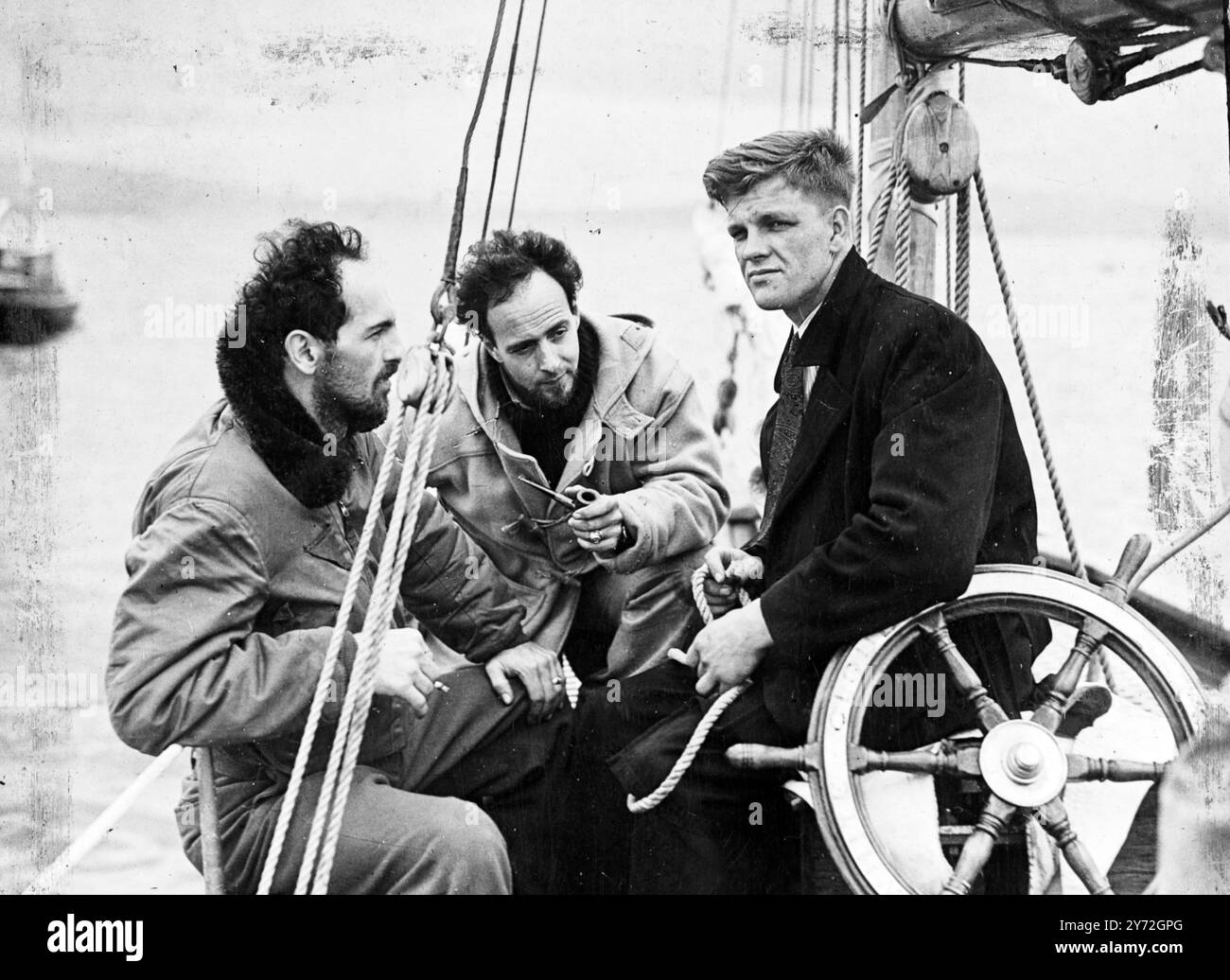 Fünf Leute brechen von Gouroc auf, um die gefährliche 5500 Meilen lange Reise nach Amerika in 63 Fuß yawl White Cloud zu versuchen. Neuer Kapitän des Schiffes ist der 22-jährige zweite Kamerad Roderick Finlayson aus Ross-shire, Schottland. Mit ihm geht es zu jungen Ex-Piloten der amerikanischen Luftwaffe und ihren Frauen. Gestern war die Party damit beschäftigt, die letzten Vorbereitungen für den langen Film zu treffen. Wenn alles gut läuft, hoffen sie, Anfang September in Maine anzukommen. Das Bild zeigt: Bereit für das Segeln an Bord der White Cloud sind der Kapitän Roderick Finlayson und zwei amerikanische Ex-Piloten Wesley Love (links) und Gordo Stockfoto