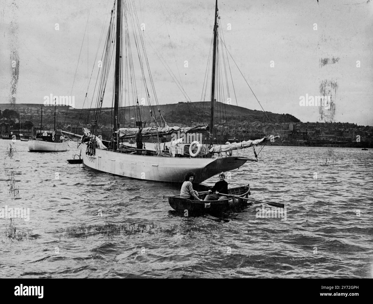 Fünf Leute brechen von Gourock auf, um die gefährliche 5500 Meilen lange Reise nach Amerika in 63 Fuß Yawl White Cloud zu versuchen. Neuer Kapitän des Schiffes ist der 22-jährige zweite Kamerad Roderick Finlayson aus Ross-shire, Schottland. Mit ihm geht es zu jungen Ex-Piloten der amerikanischen Luftwaffe und ihren Frauen. Gestern war die Party damit beschäftigt, die letzten Vorbereitungen für den langen Film zu treffen. Wenn alles gut läuft, hoffen sie, Anfang September in Maine anzukommen. Das Bild zeigt: Zwei der Crew, Mrs. Clark (Rudern) und Mrs. Love, Ehefrauen der amerikanischen Ex-Piloten, verlassen White Cloud, um ein letztes Einkaufen zu machen Stockfoto