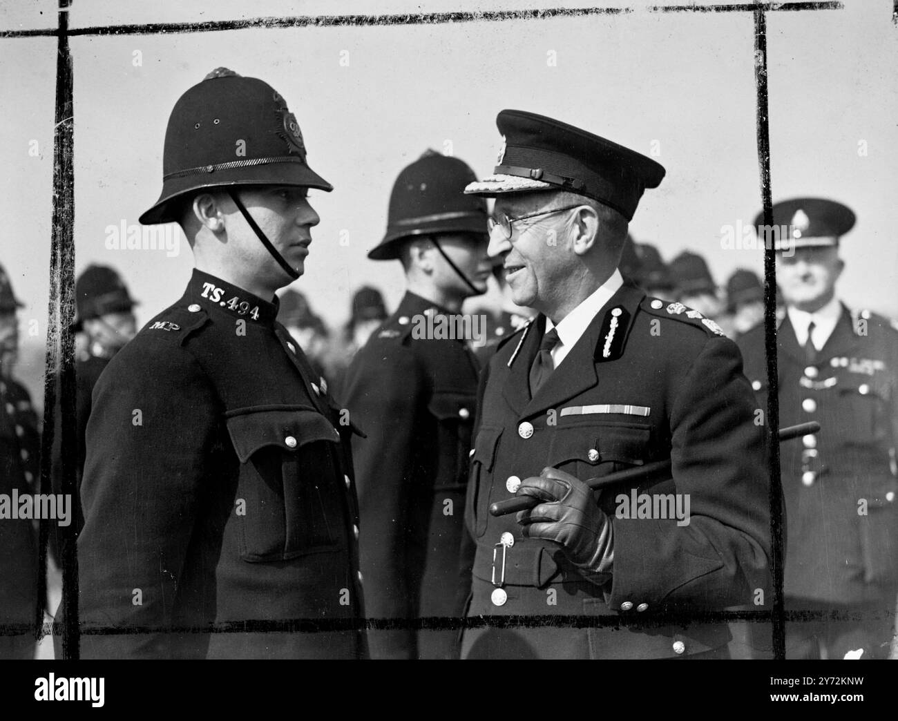 50 Rekruten, er hat gerade ihre dreimonatige Ausbildung für die Metropolitan Police Force abgeschlossen, nahm an einem "Ausscheiden" der Wut an der Metropolitan Police Training School in Hendon bei London Teil. Sir Harold Scott, Polizeikommissar der Metropole, hat mit einem der neuen "Bobbies" in London, dem 21-jährigen John Garrett, einem Iren, geplaudert, dem er während des Krieges mit den Ostlanken in Nordafrika, Italien und Palästina diente. - 14. April 1947 Stockfoto