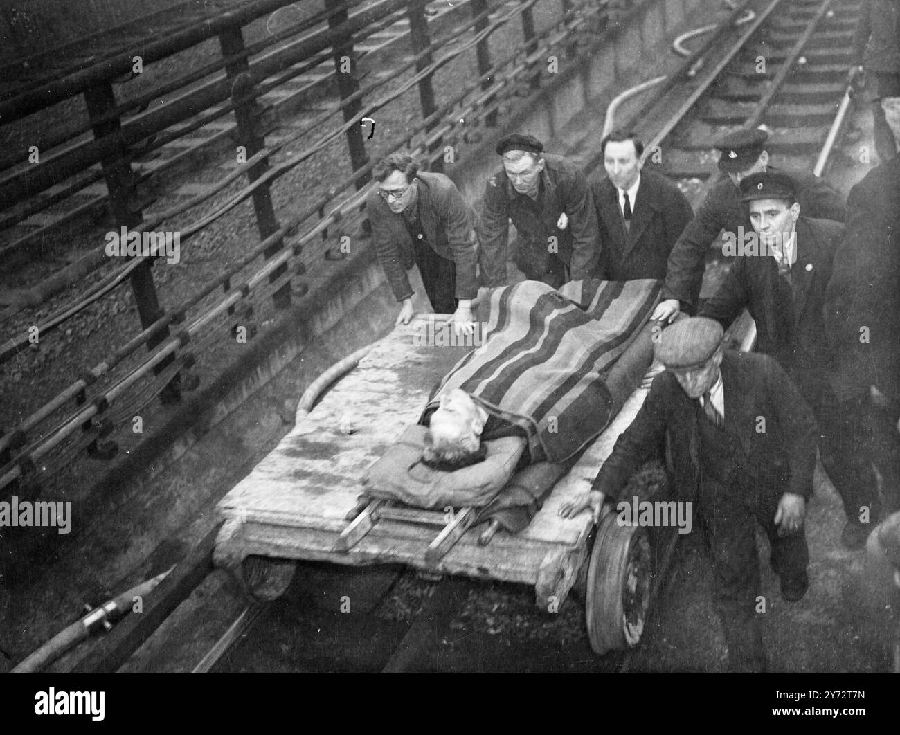 Feuerwehrleute, Polizei und Eisenbahnarbeiter benutzten spezielle Schneidgeräte, um L.P.T.B. Mitarbeiter zu befreien, die in mehreren Wagen des U-Bahn-Zuges gefangen waren, der mit einem anderen Zug im unterirdischen Abschnitt des östlichen Abschnitts der zentralen Linie zusammenfiel, der gestern für die Öffentlichkeit geöffnet wurde. Beide Züge waren zum Zeitpunkt des Unfalls leer, der sich auf einer Schleifenstrecke ereignete, auf der Züge über den eigentlichen Bahnhof Stratford hinaus gedreht werden können. Das Bild zeigt: Einer der verletzten Männer, nachdem er aus dem Wrack befreit wurde, wurde aus dem Wrack geholt Stockfoto