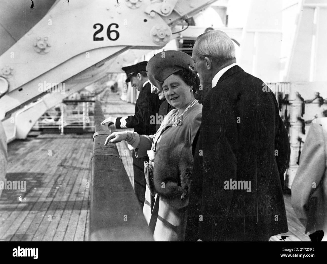 Mit der Queen und den beiden Prinzessinnen an Bord wird der 85.000 t schwere Cunnard - White Star Liner Queen Elizabeth an der Nordostküste von Arran, Schottland, durch die sie ihre Offizielle Schnelltests durchlaufen. Das Bild zeigt Ihre Majestät die Königin, zusammen mit Sir Percy Bates, dem Vorsitzenden des Liners, untersucht die Initialen der Soldaten, die während ihres Dienstes als Kriegstransport auf die Schiene des Schiffes gehauen wurden. Fotos, die während der Geschwindigkeitsprüfungen der Königin Elisabeth während ihrer Geschwindigkeitsprüfungen und des Firth of Clyde aufgenommen wurden. 8. Oktober 1946 Stockfoto