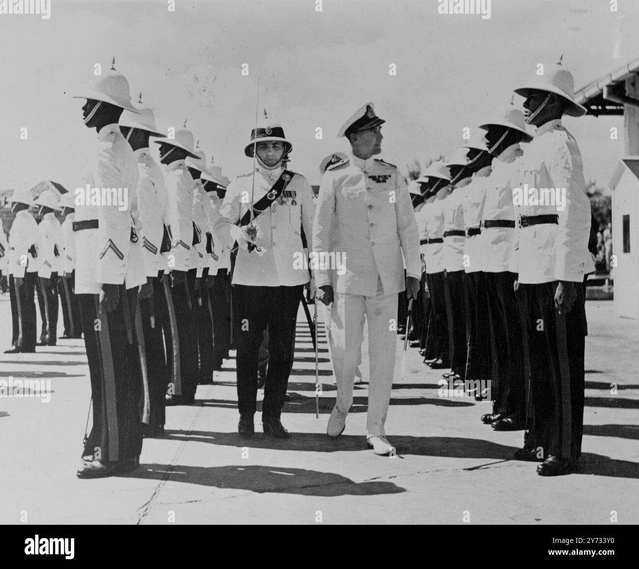 ADML A.E.M.B.Cunningham Graham, CBE, R.N., kommandiert die 10th Cruiser Squadron, die eine Ehrengarde der Polizei der Bahamas in Nassau, Bahamas, Westindien inspiziert, als sein Flaggschiff HMS Birmingham für einen offiziellen Besuch ankerte. Begleitperson des ADML-Capt E.W. Sears von der Polizei der Bahamas (links). 17. April 1946 Stockfoto