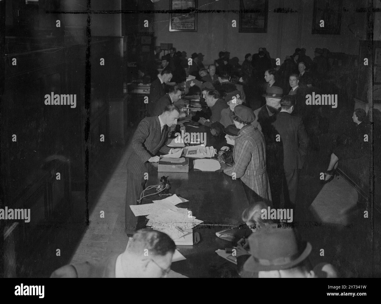 Kunden, die Kataloge mit Agenten der Reiseagentur Thomas Cook, London.1946, durchsehen Stockfoto