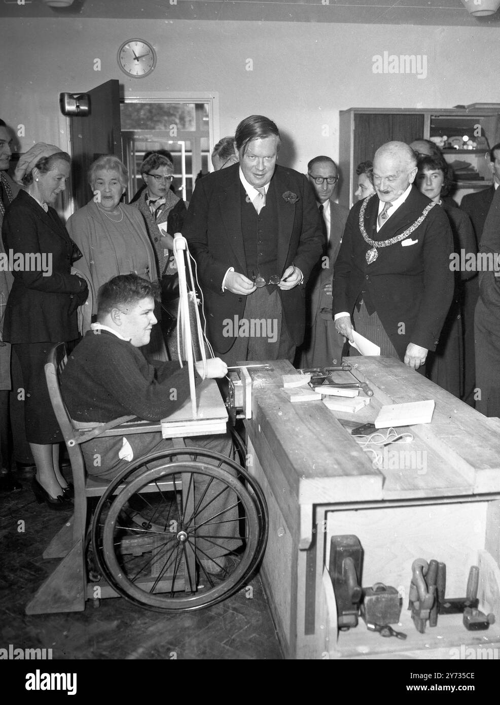 Sir Edward Boyle , Parlamentarischer Sekretär des Bildungsministers (Zentrum) spricht mit Michael Gauden , 14 Jahre alt , in der Holzwerksklasse der Franklin Delano Roosevelt Schule für körperbehinderte Kinder , die gerade offiziell in Hampstead eröffnet worden war . Auf der rechten Seite befindet sich der Bürgermeister von Hampstead , Lieutenant Col H Ashley-Scarlett . 3. Oktober 1957 Stockfoto