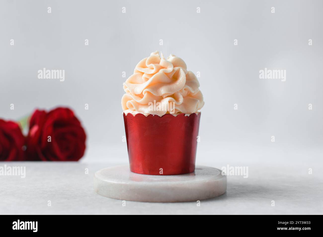 Rote Cupcakes mit rosafarbenem Buttercremewirl, Cupcakes in roter Folienfolie mit rosafarbener Buttercreme Stockfoto