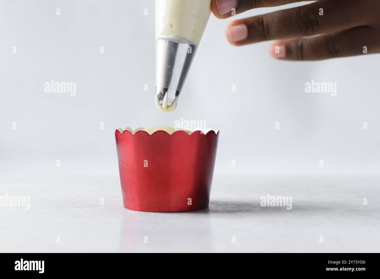 Buttercreme auf einem Cupcake pürieren, Cupcakes dekorieren, hohe Zuckerguss von Hand auf Cupcakes putzen, der Prozess der Dekoration von Cupcake Stockfoto