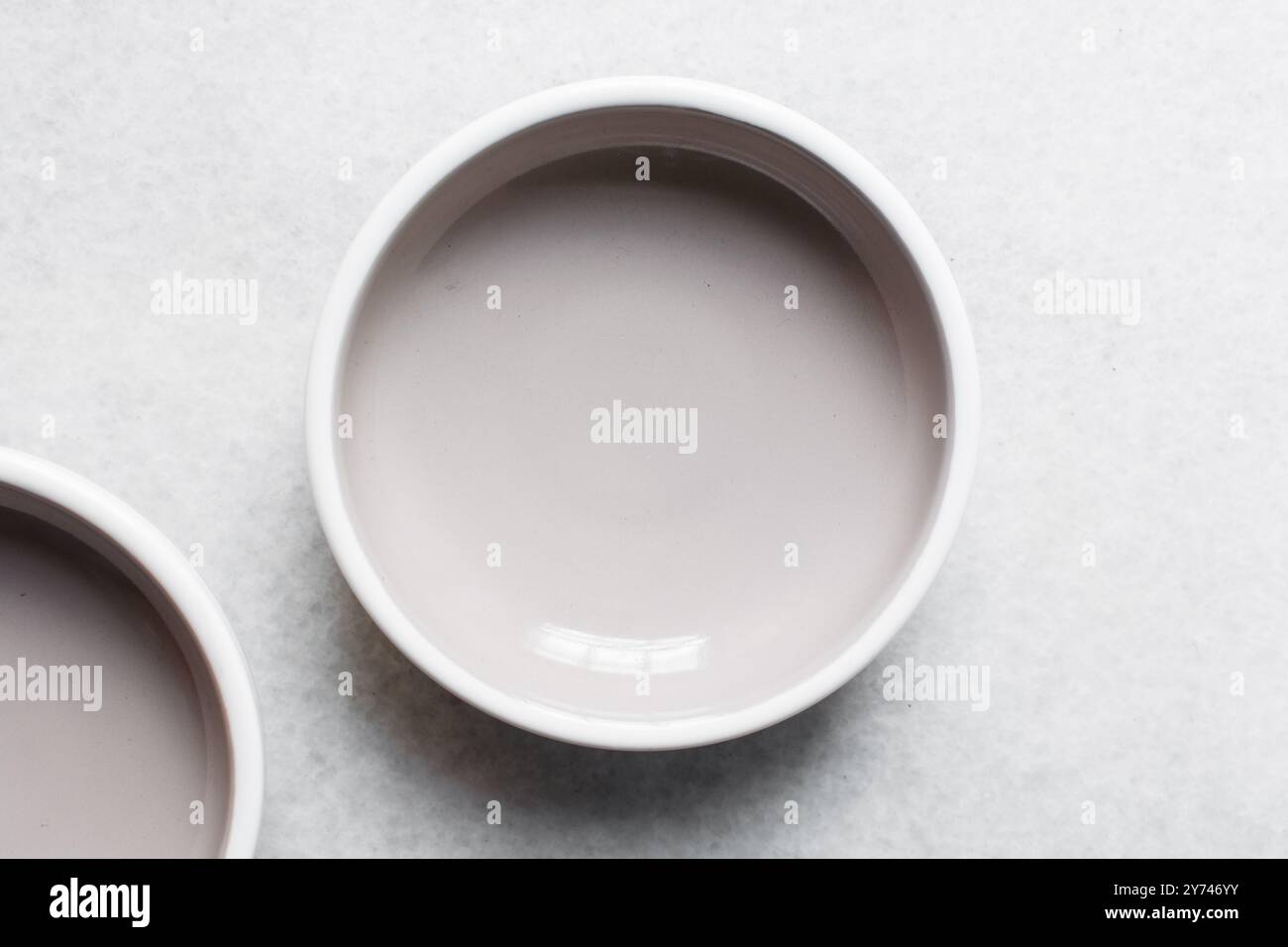 Blick von oben auf graue Keramikplatten auf einem Marmortisch, graue taupefarbene Keramikplatte mit minimalistischem Design Stockfoto