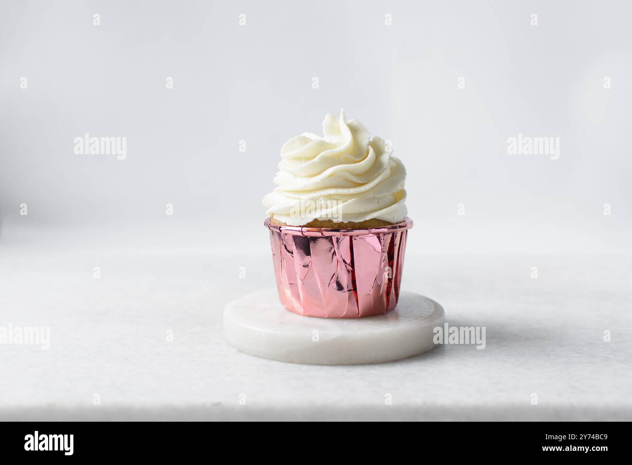 Rosafarbene Cupcakes mit hohem Buttercremewirl, Cupcakes in rosafarbenen Folieneinlagen mit Vanille-Buttercreme, mattierte Cupcakes auf weißem Hintergrund Stockfoto