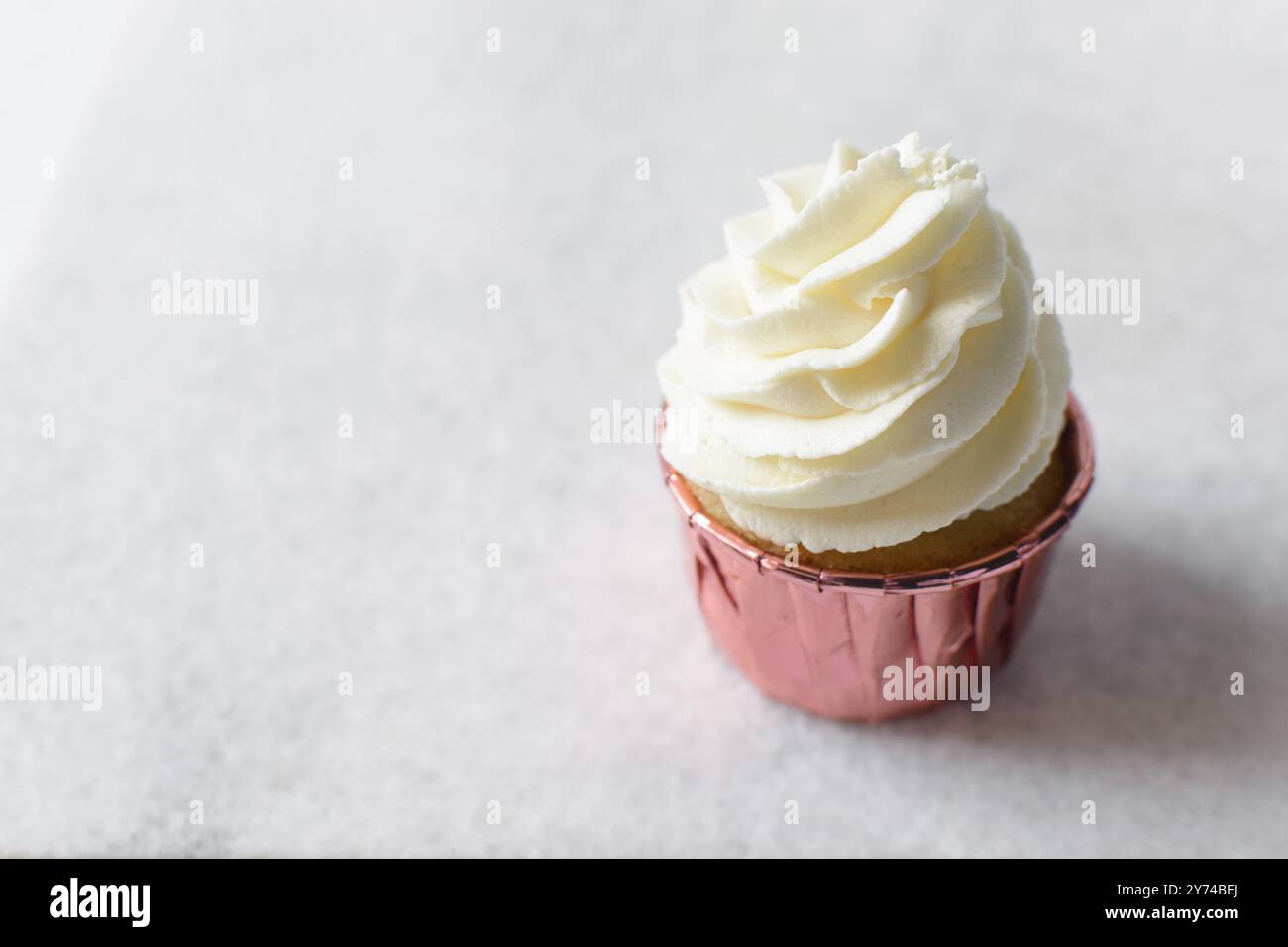 Rosafarbene Cupcakes mit hohem Buttercremewirl, Cupcakes in rosafarbenen Folieneinlagen mit Vanille-Buttercreme, mattierte Cupcakes auf weißem Hintergrund Stockfoto