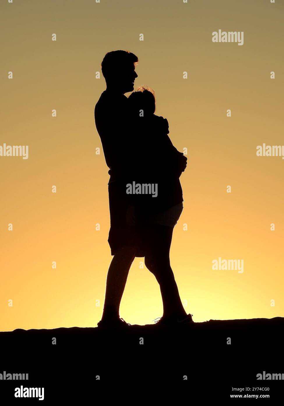 Eine Reihe von fesselnden Silhouetten, die ein Paar mit zarten Momenten bei Sonnenuntergang zeigt und eine ruhige und romantische Atmosphäre schafft. Stockfoto