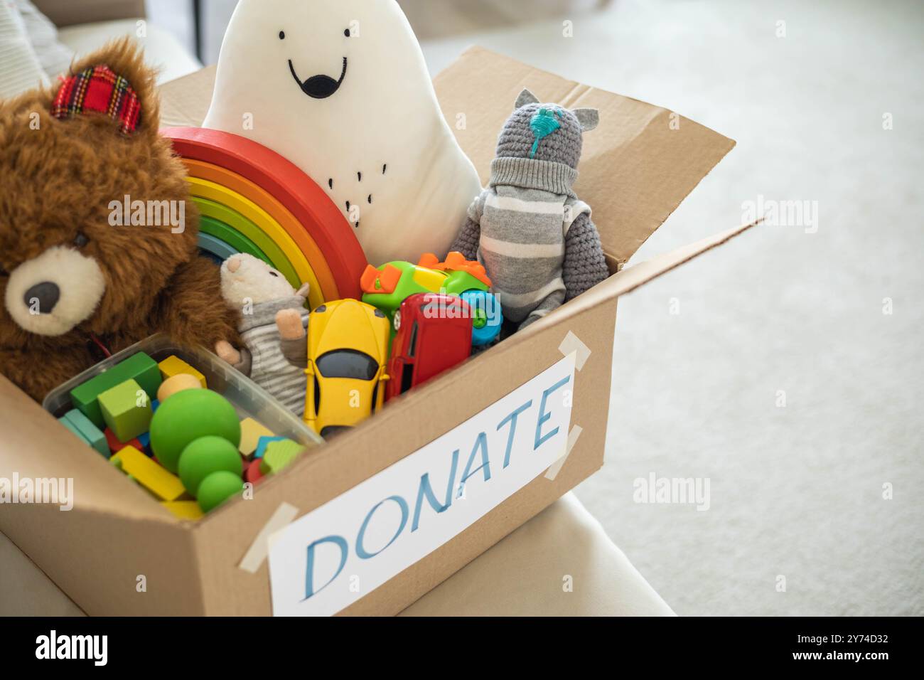 Auf der Wohnzimmercouch befindet sich eine Schachtel voller Spielzeug für Spenden. Teddybär Kuschelspielzeug Stockfoto