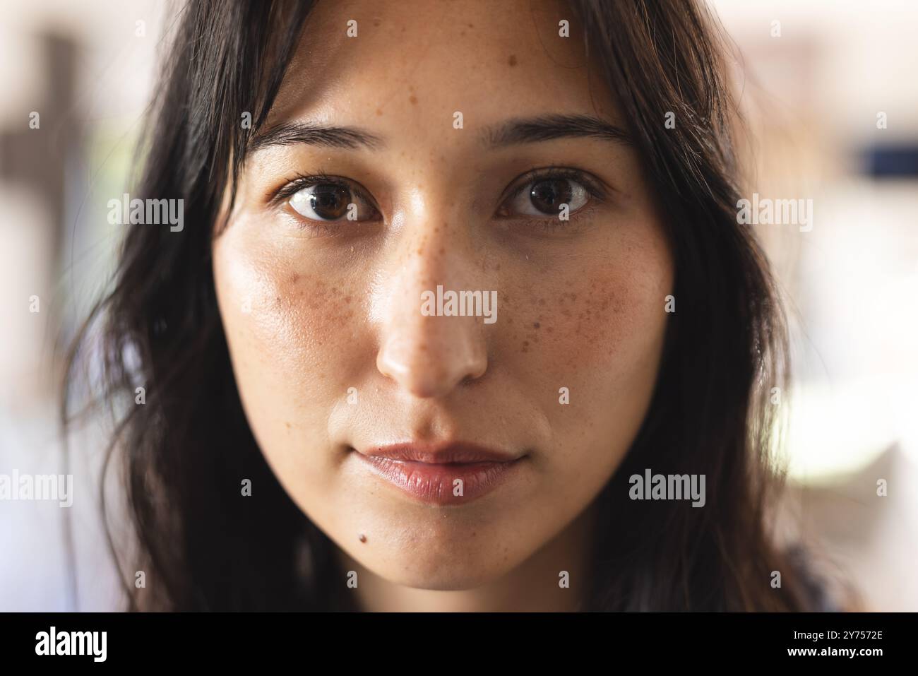 Nahaufnahme einer Frau mit Sommersprossen, die mit ernstem Ausdruck in die Kamera schaut, zu Hause Stockfoto