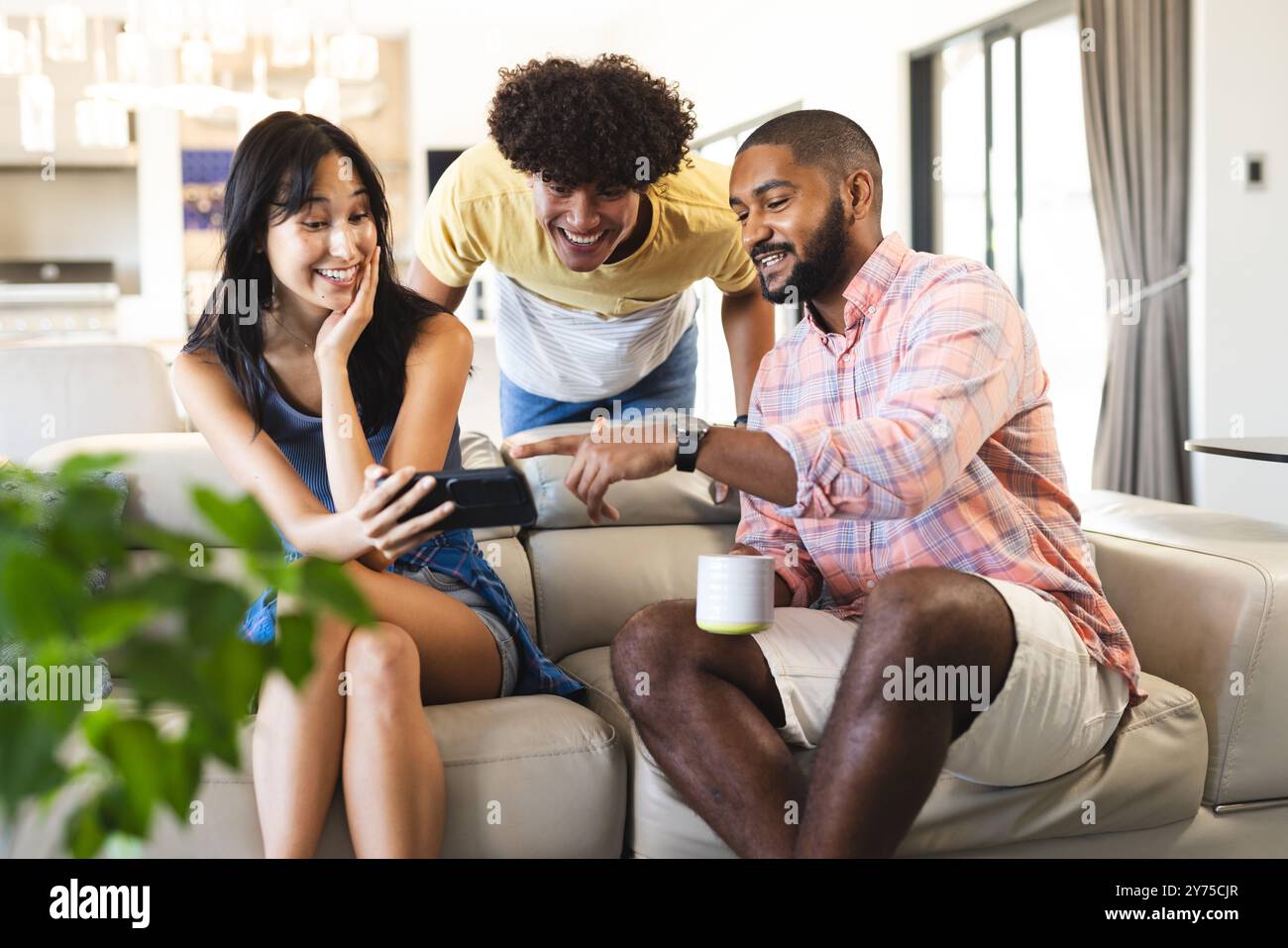 Auf dem Smartphone etwas anschauen, verschiedene Freunde abhängen, die gemeinsame Zeit genießen, zu Hause Stockfoto
