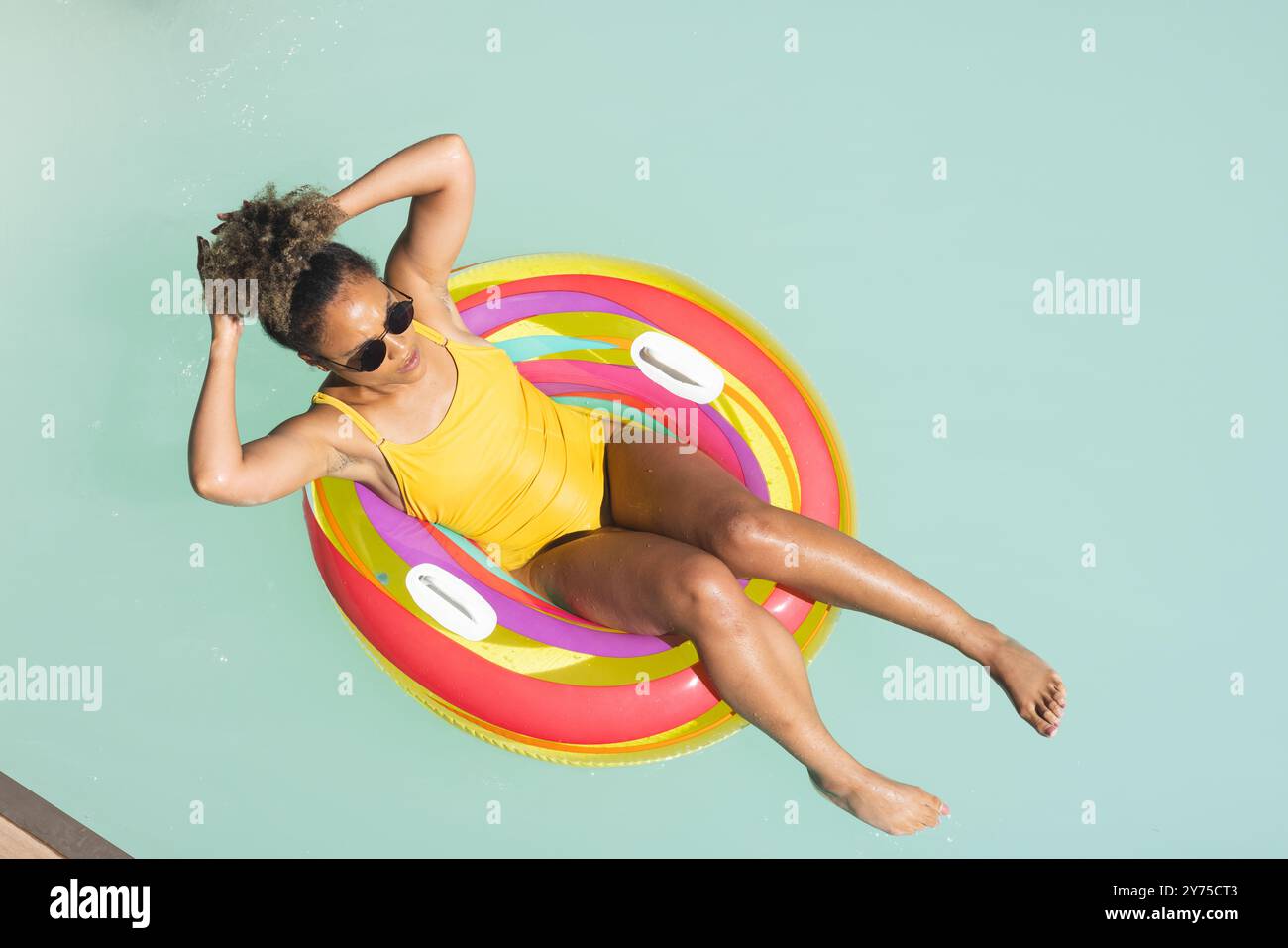 Entspannen Sie sich auf dem farbenfrohen Schwimmbecken, Frau in gelben Badeanzügen genießt den Sommertag, zu Hause Stockfoto